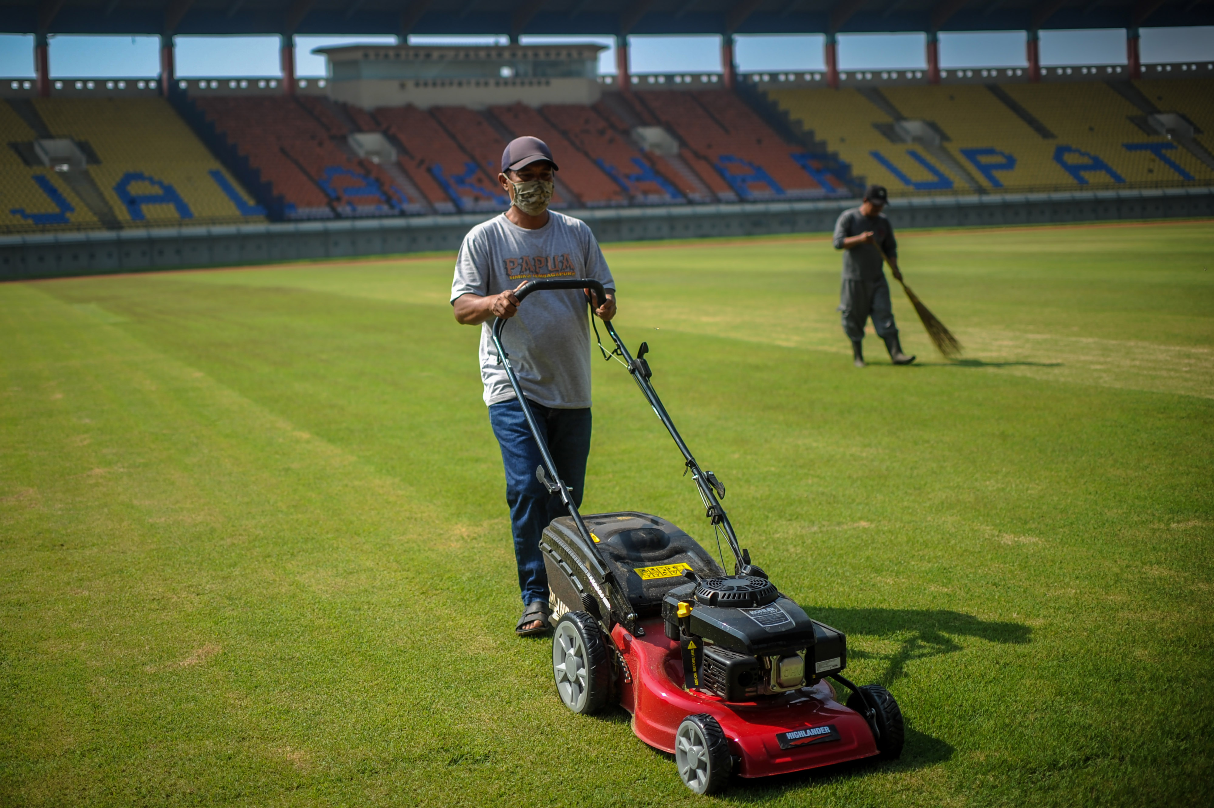 Pekerja memotong rumput di Stadion Si Jalak Harupat, Kabupaten Bandung, Jawa Barat.