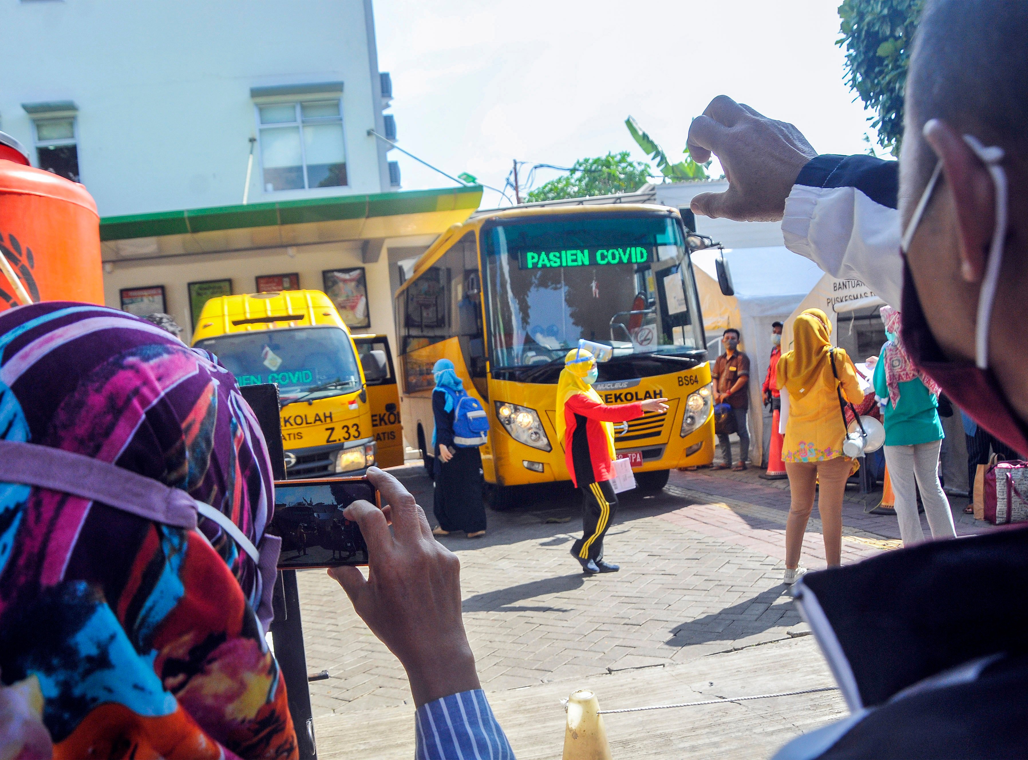 Keluarga memberi semangat sebelum pasien covid-19 berangkat dengan bus sekolah menuju RSD Wisma Atlet Kemayoran di Jakarta, Jumat (13/11).