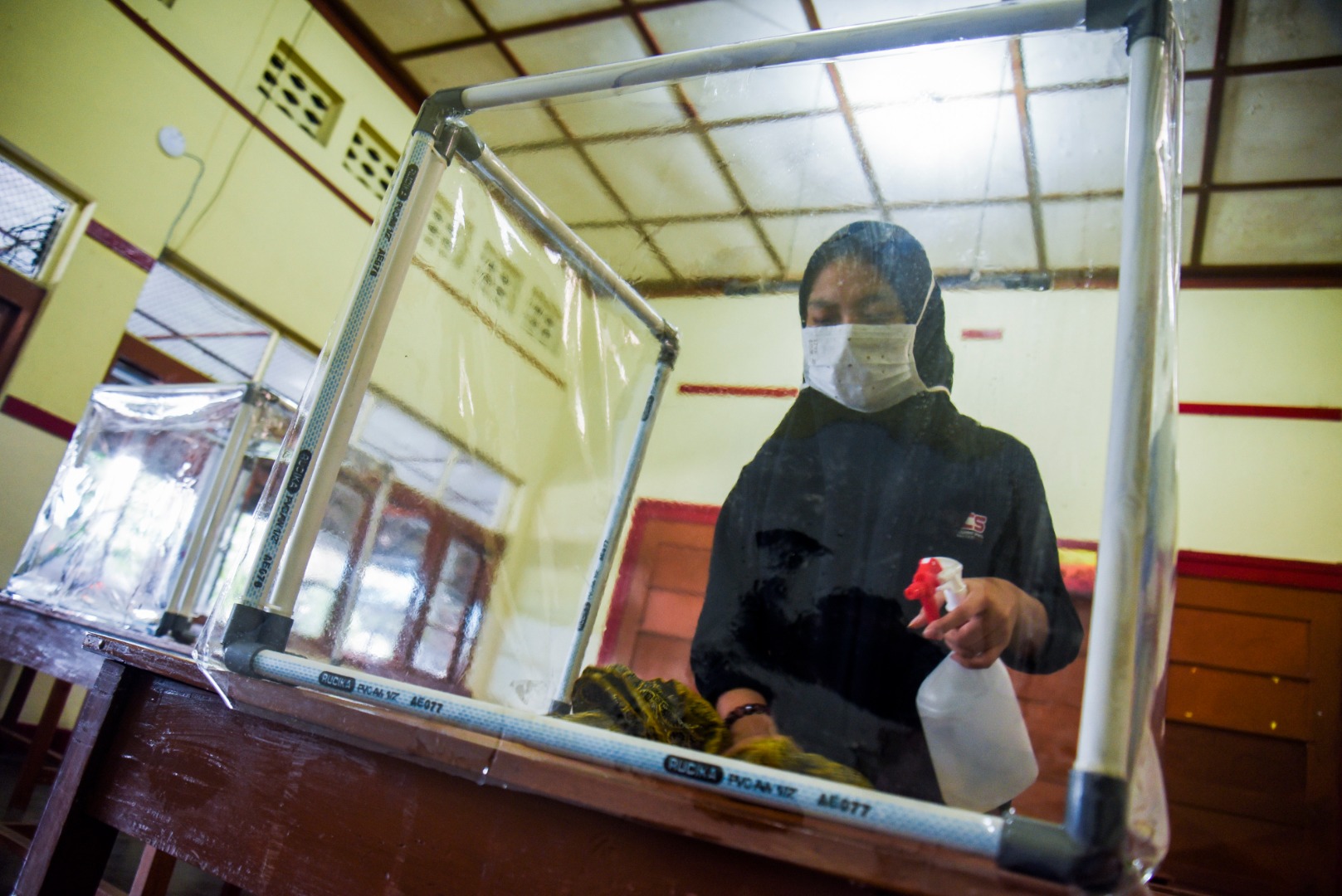 Pengurus OSIS membersihkan meja dan kotak pelindung jelang kegiatan belajar mengajar tatap muka di SMA Negeri 4, kota Sukabumi.