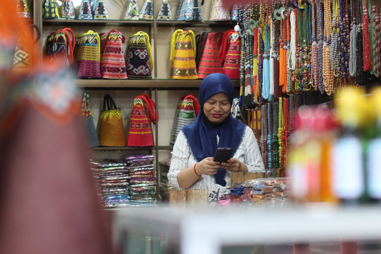 Pedagang melihat pesanan melalui gawai di Pasar Inpres Kebun Sayur, Balikpapan. 