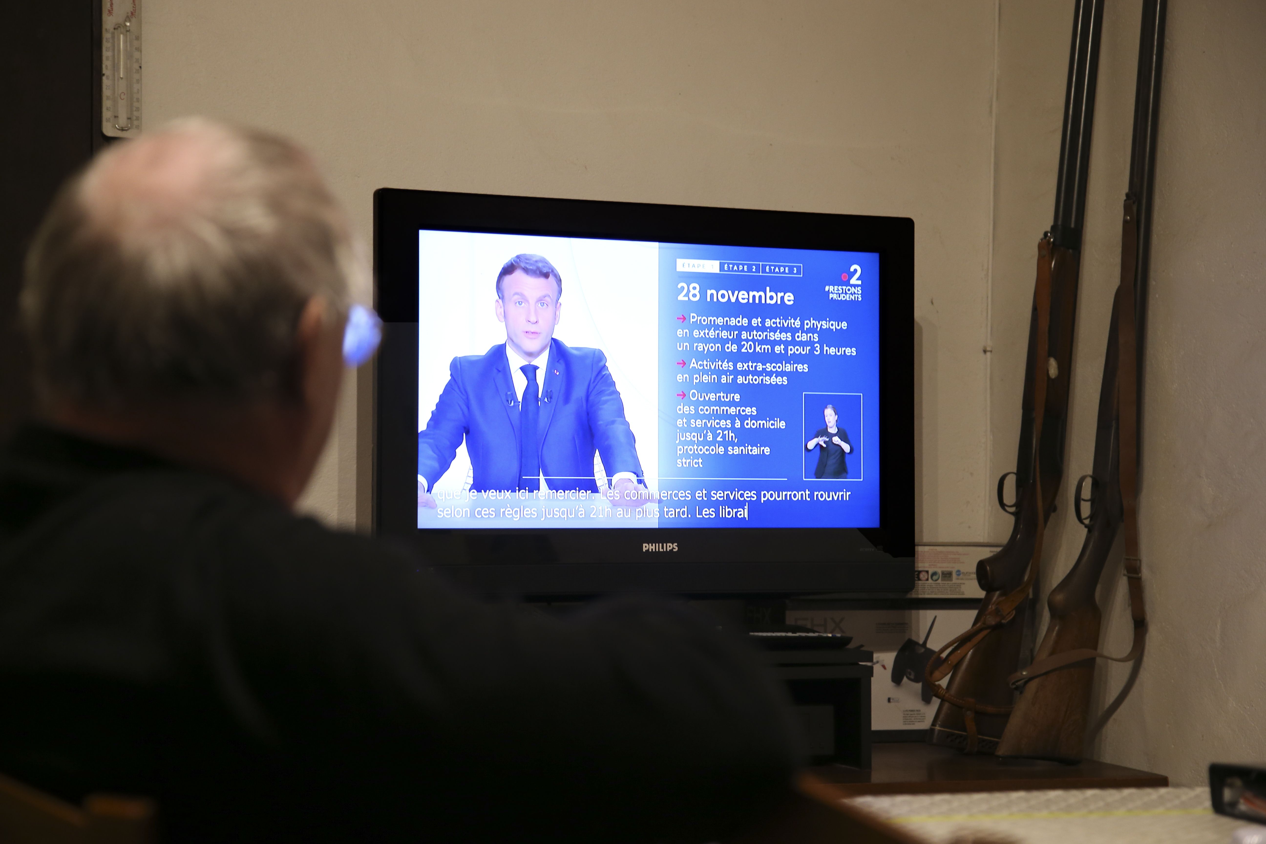 Seorang warga Prancis menyaksikan pidato Presiden Emmanuel Macron mengenai rencana pencabutan lockdown nasional pada 5 Desember di TV.