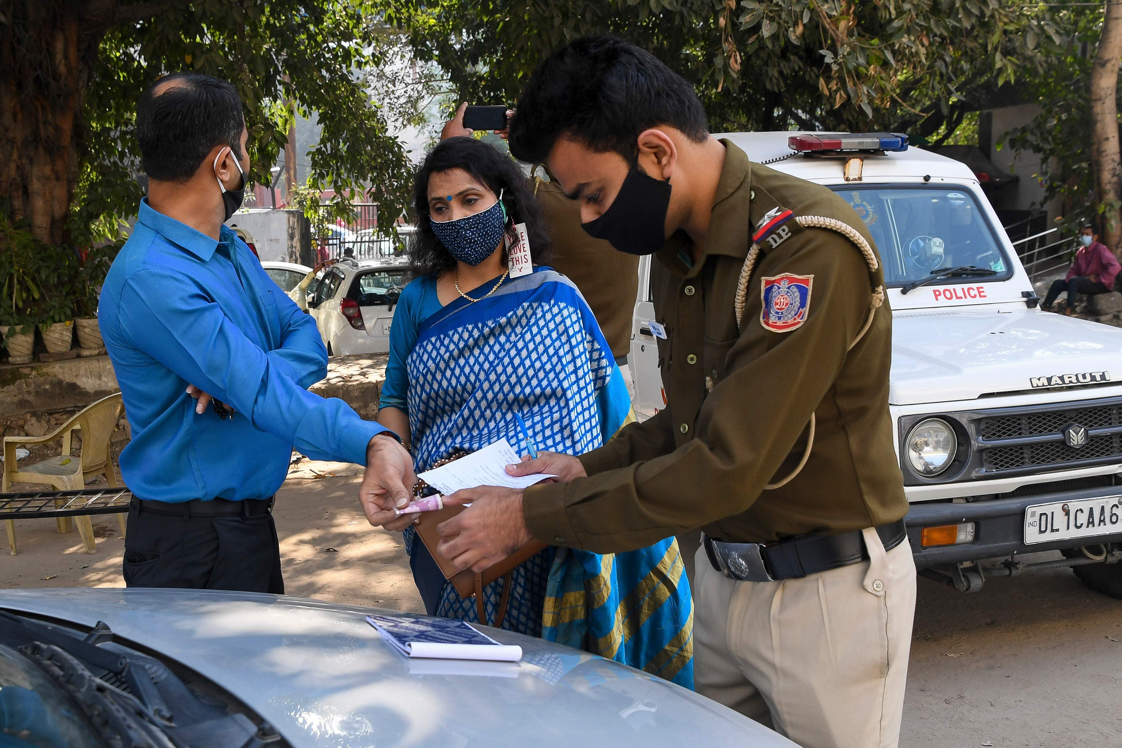 Polisi mendenda warga yang tidak mengenakan masker di New Delhi, India.