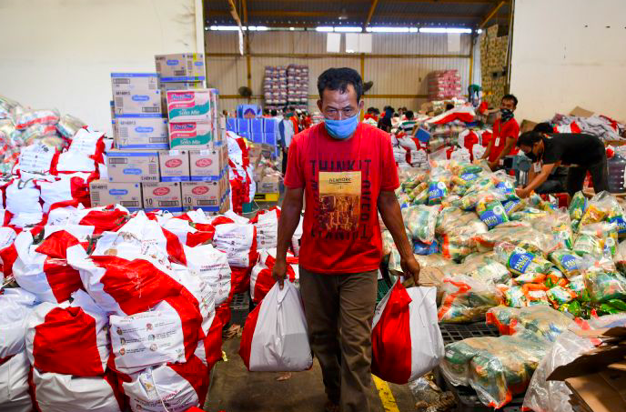 Pekerja membawa paket bantuan sosial (bansos) yang akan disalurkan di Gudang Food Station Cipinang, Jakarta, Rabu (22/4/2020). 