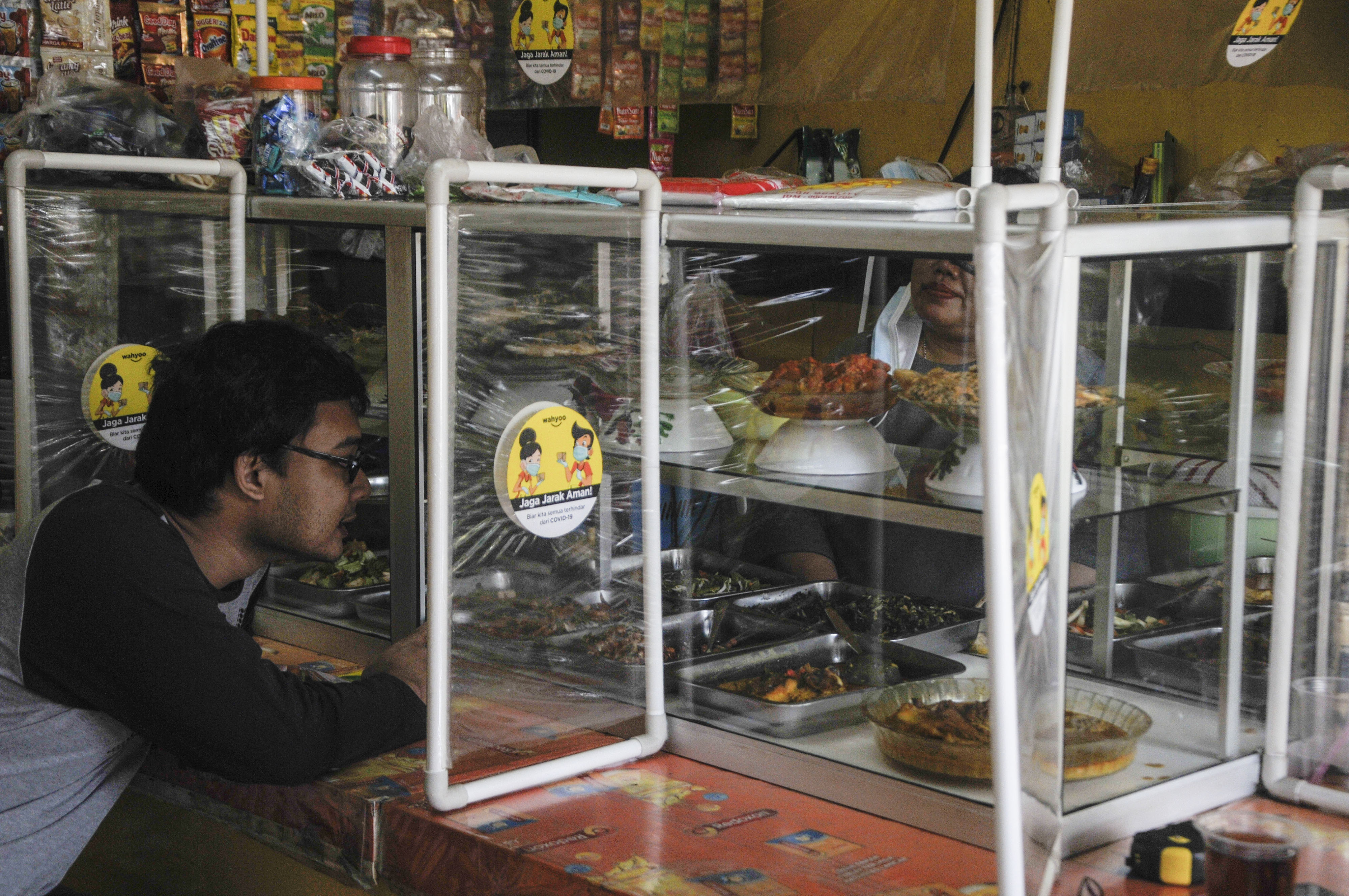 Seorang warga memesan makanan di rumah makan yang menerapkan jaga jarak di Duren Sawit, Jakarta Timur, Jumat (13/11/2020).