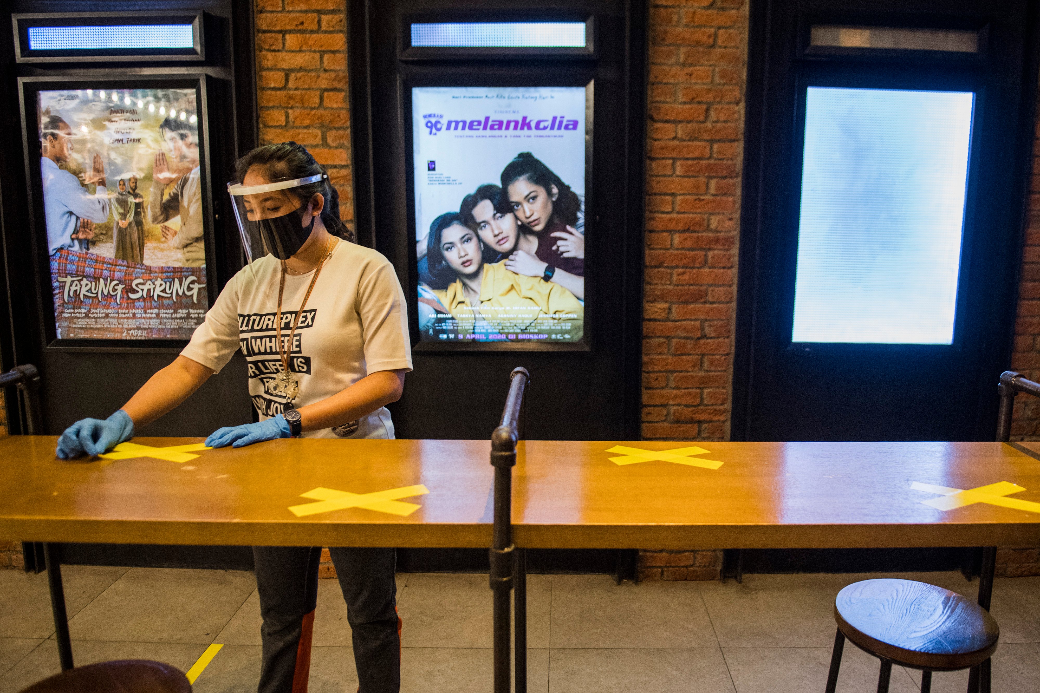 Pekerja memasang tanda jaga jarak saat simulasi pembukaan dan peninjauan tempat hiburan bioskop CGV Cinemas di Bandung 