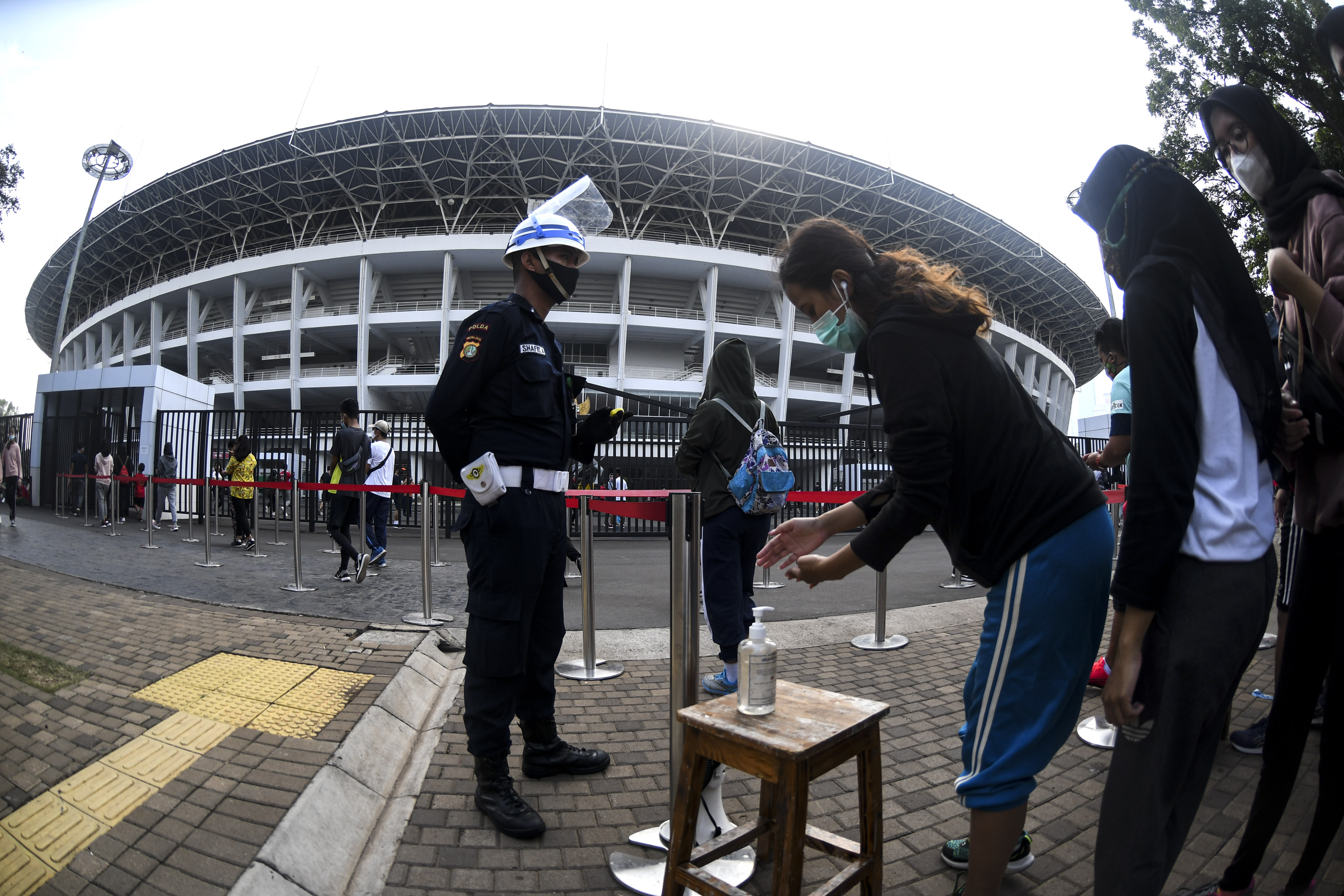 Warga menggunakan cairan pembersih tangan saat antre untuk berolahraga di Stadion Utama, Kompleks Gelora Bung Karno (GBK), Jakarta.