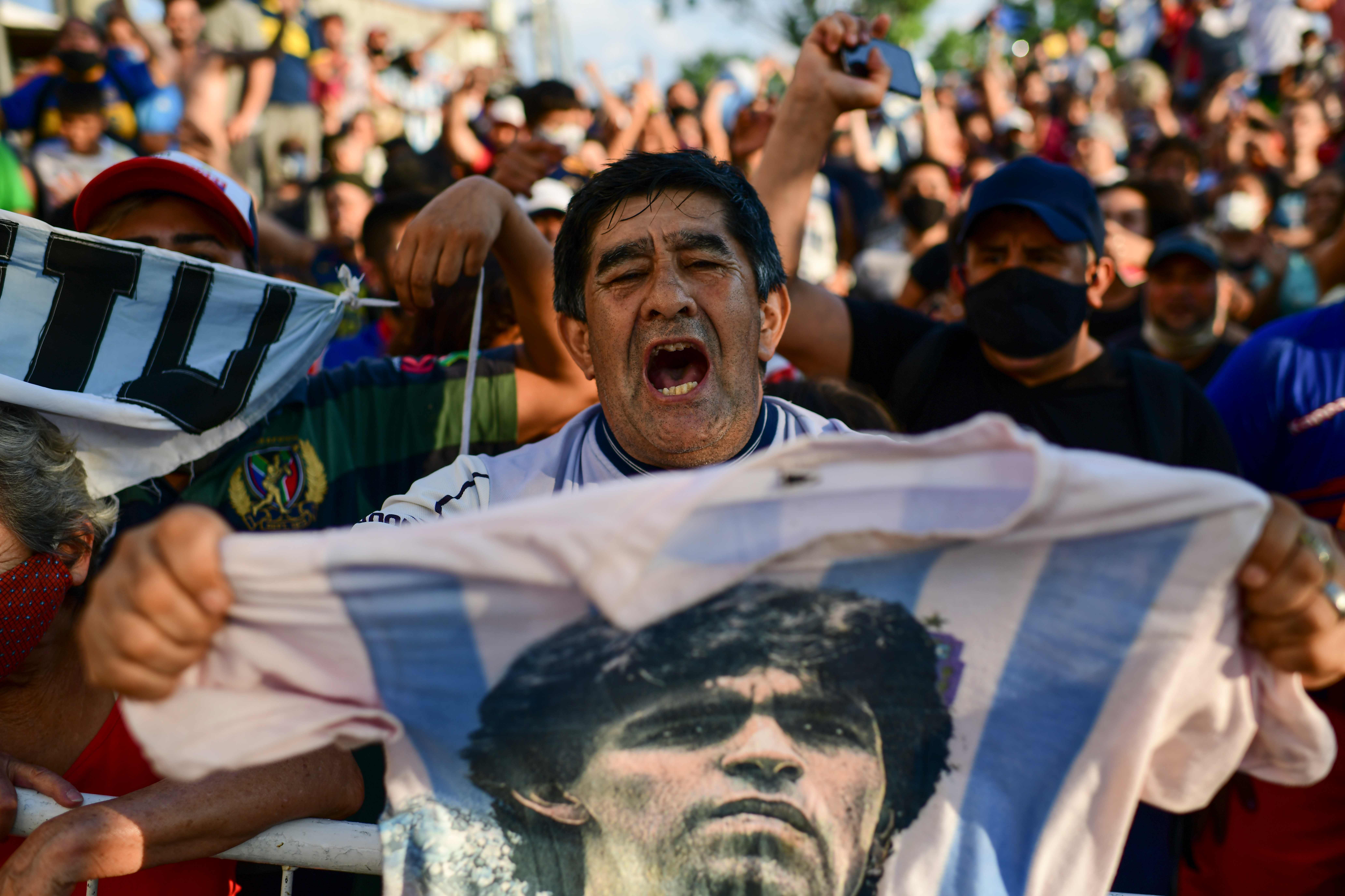 Pendukung Diego Maradona berduka sambil membentangkan kaos bergambar sang legenda Diego Maradona di San Fernando, Buenos Aires, Argentina.