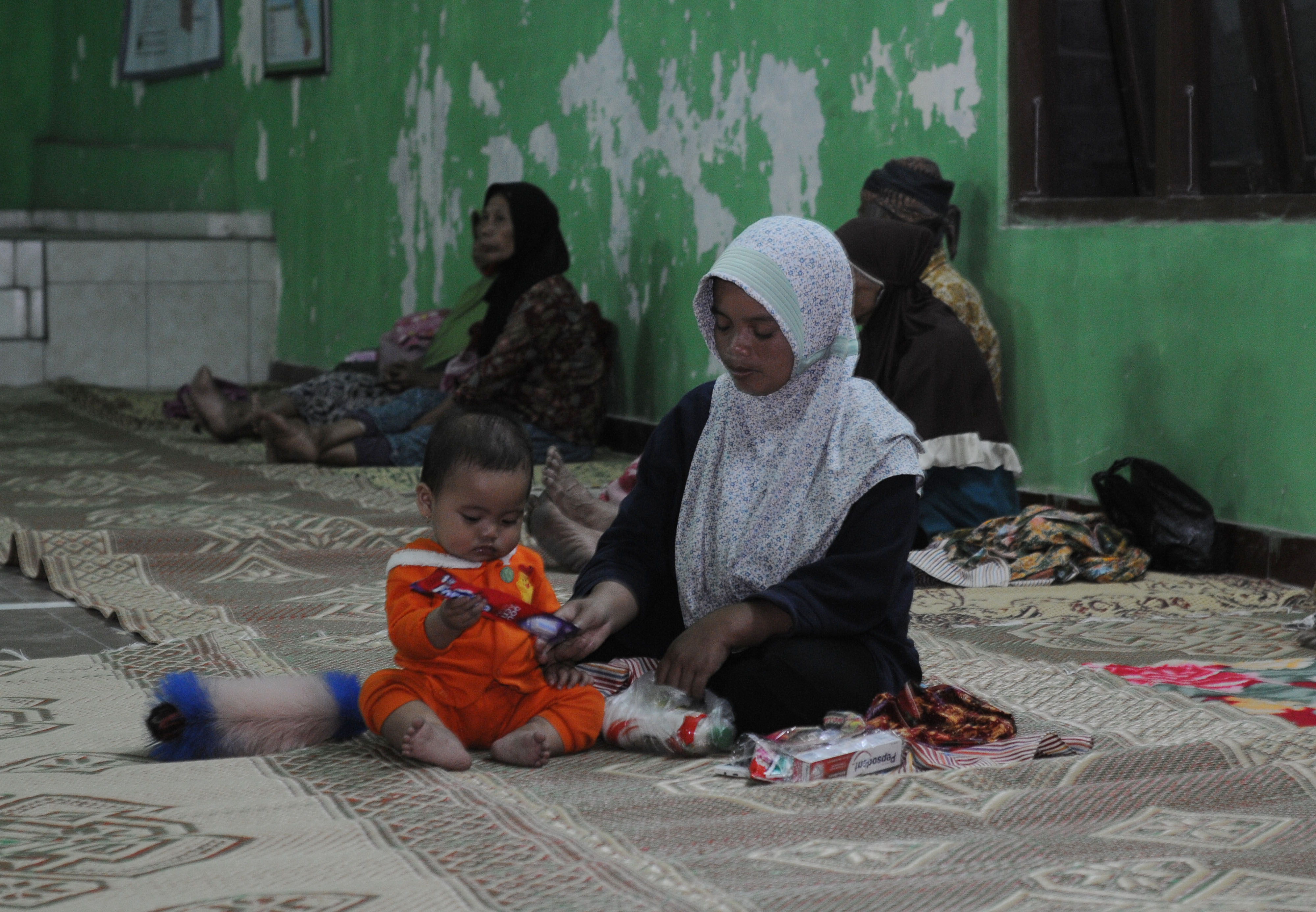 Seorang ibu bermain dengan anaknya saat berada di tempat pengungsian di Kantor Desa Balerante, Kemalang, Klaten, Jawa Tengah.