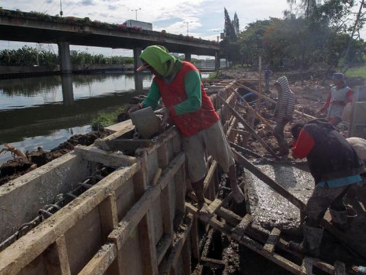   Pekerja menyelesaikan proyek peninggian tanggul sungai di Ancol, Jakarta Utara