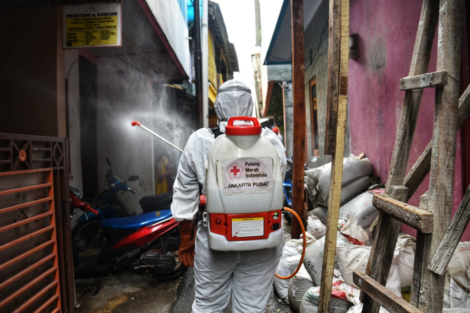 Petugas dari Palang Merah Indonesia (PMI) Kecamatan Menteng melakukan penyemprotan cairan disinfektan di kawasan yang menjadi zona merah