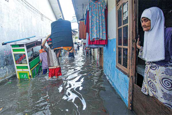 Warga berjalan melewati banjir yang melanda permukiman di Kemang Utara, Jakarta