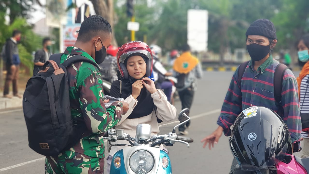 Personel TNI dan mahasiswa membagikan masker kepada pengendara kendaraan bermotor di Kota Maumere.