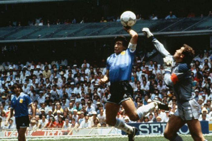Penyerang Argentina Diego Maradona mencetak gol menggunakan tangan ke gawang Inggris yang dikawal Peter Shilton.