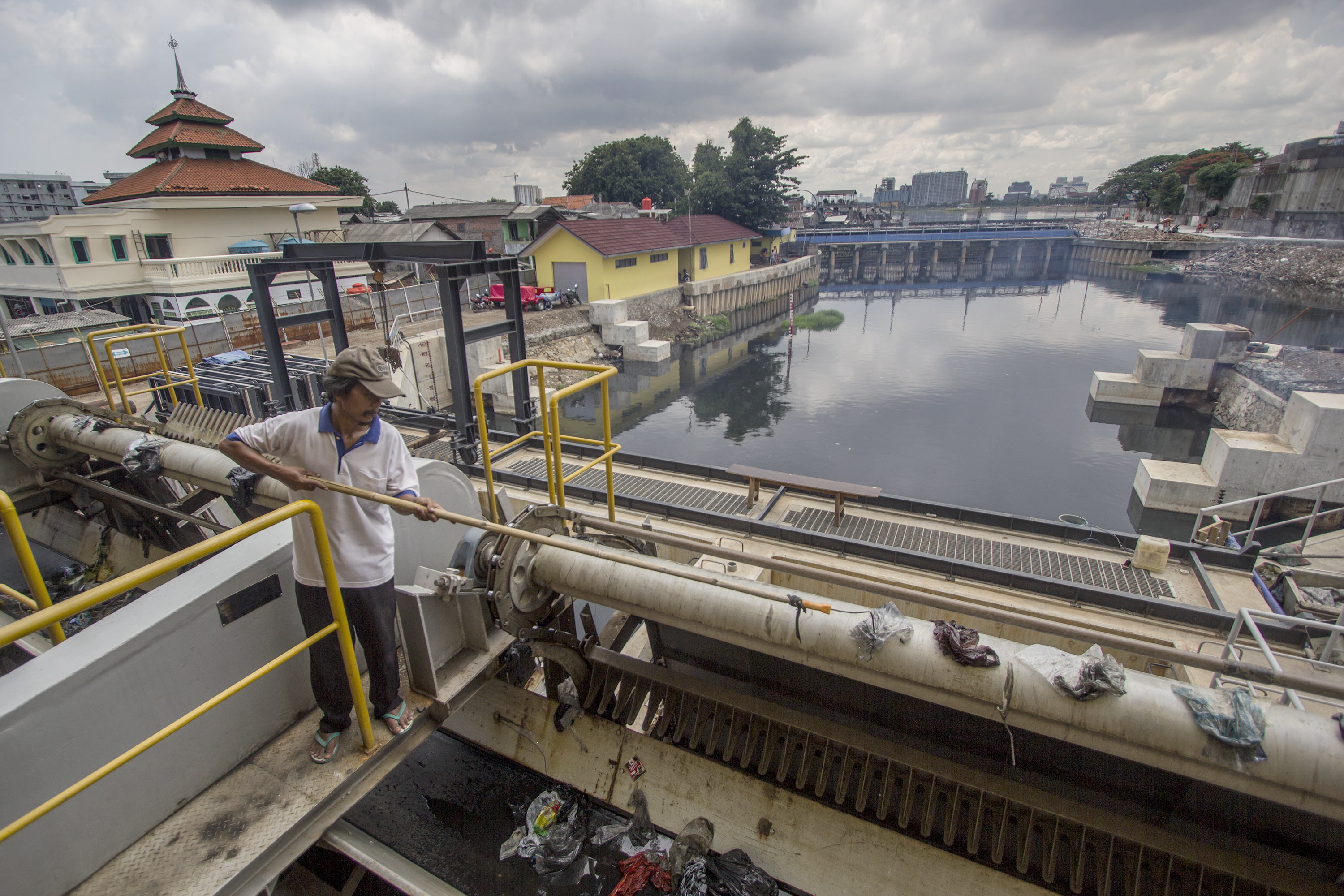 Petugas merapihkan sampah yang tersangkut di Stasiun Pompa Pluit, Jakarta, 
