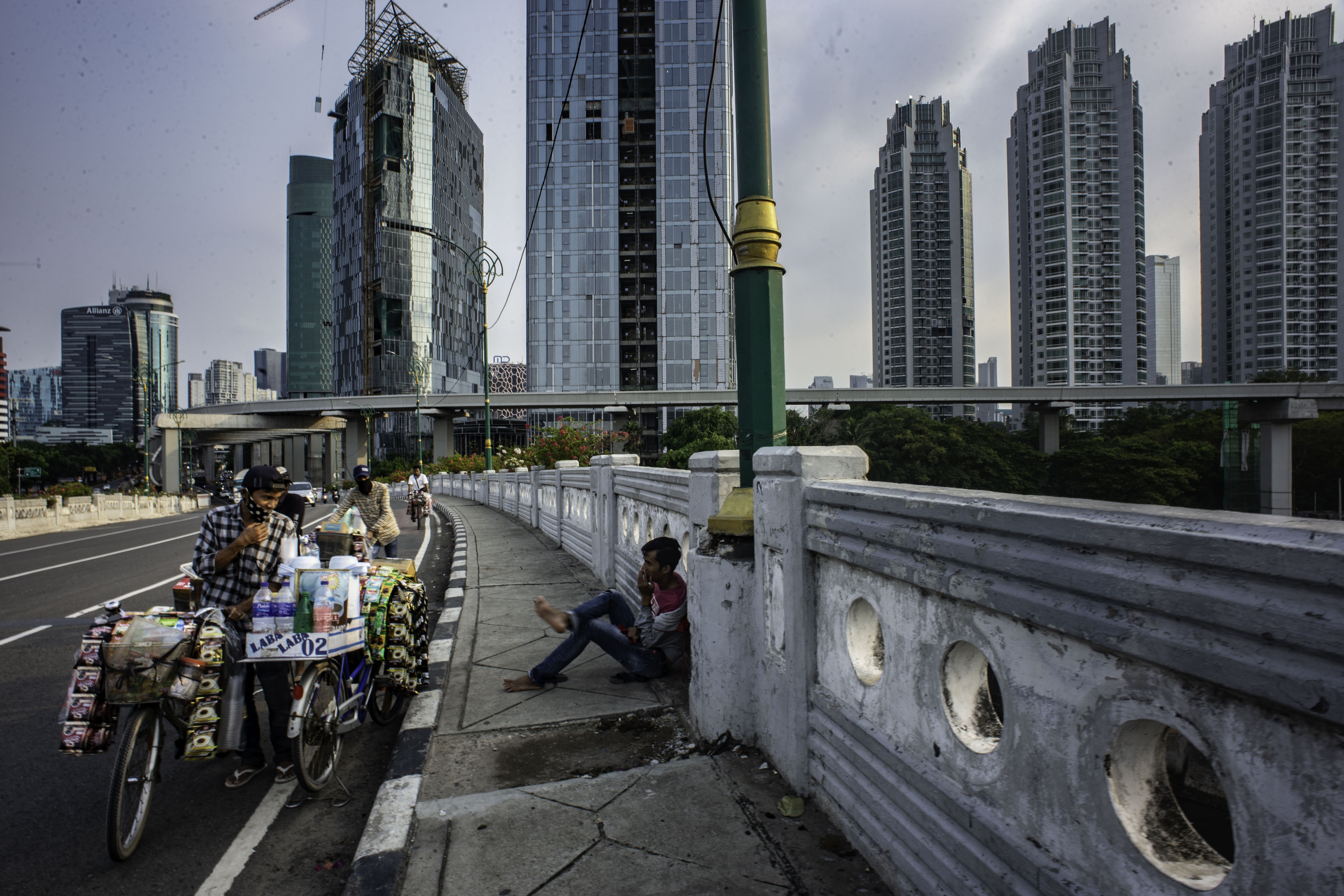 REALISASI PEMULIHAN EKONOMI NASIONAL: Pedagang minuman beristirahat dengan latar belakang gedung bertingkat di Jakarta, Selasa (6/10/2020).