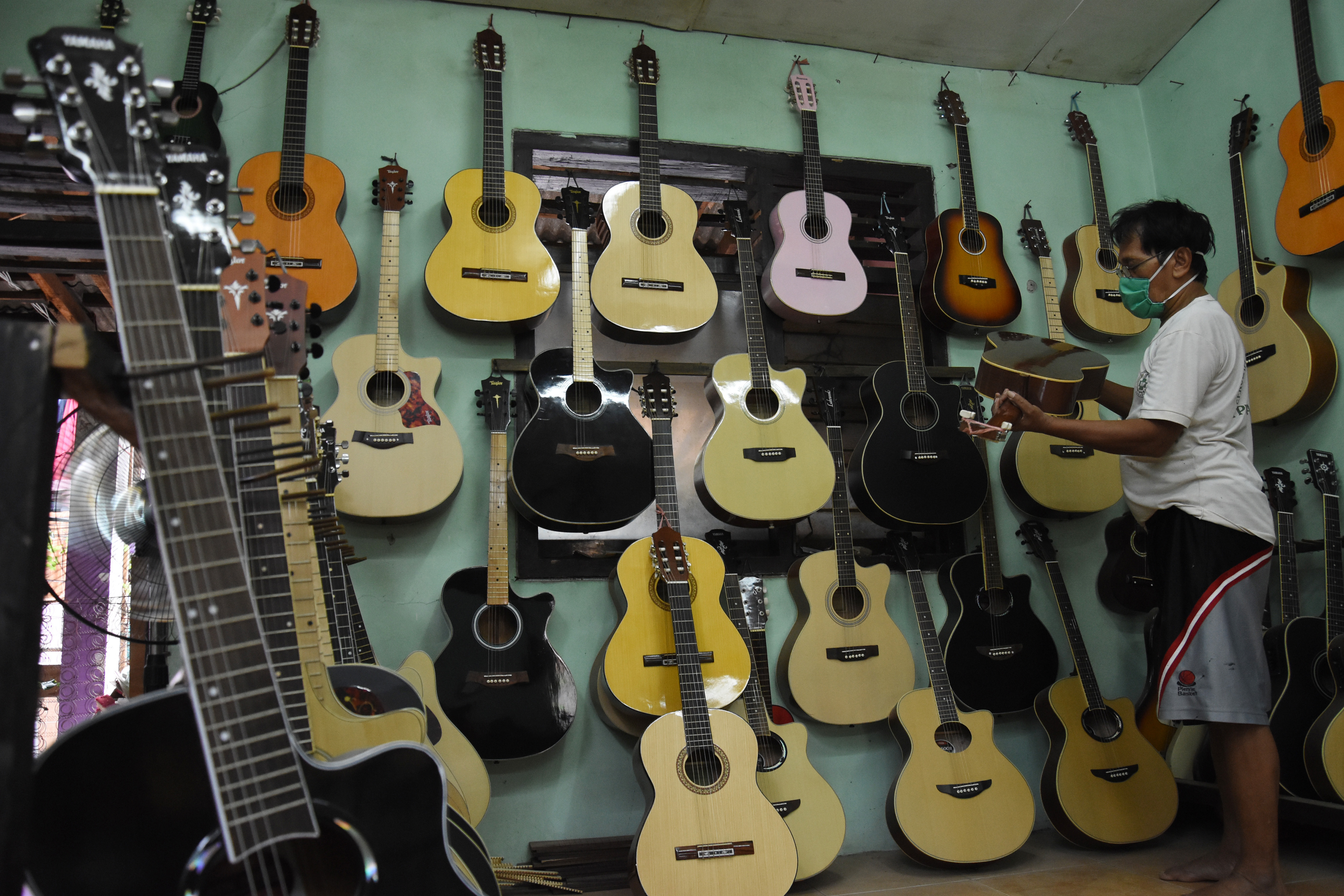  Perajin mengecek kualitas gitar yang telah dibuat di sentra produksi dan perbaikan gitar rumahan di kawasan Pasar Minggu, Jakarta.