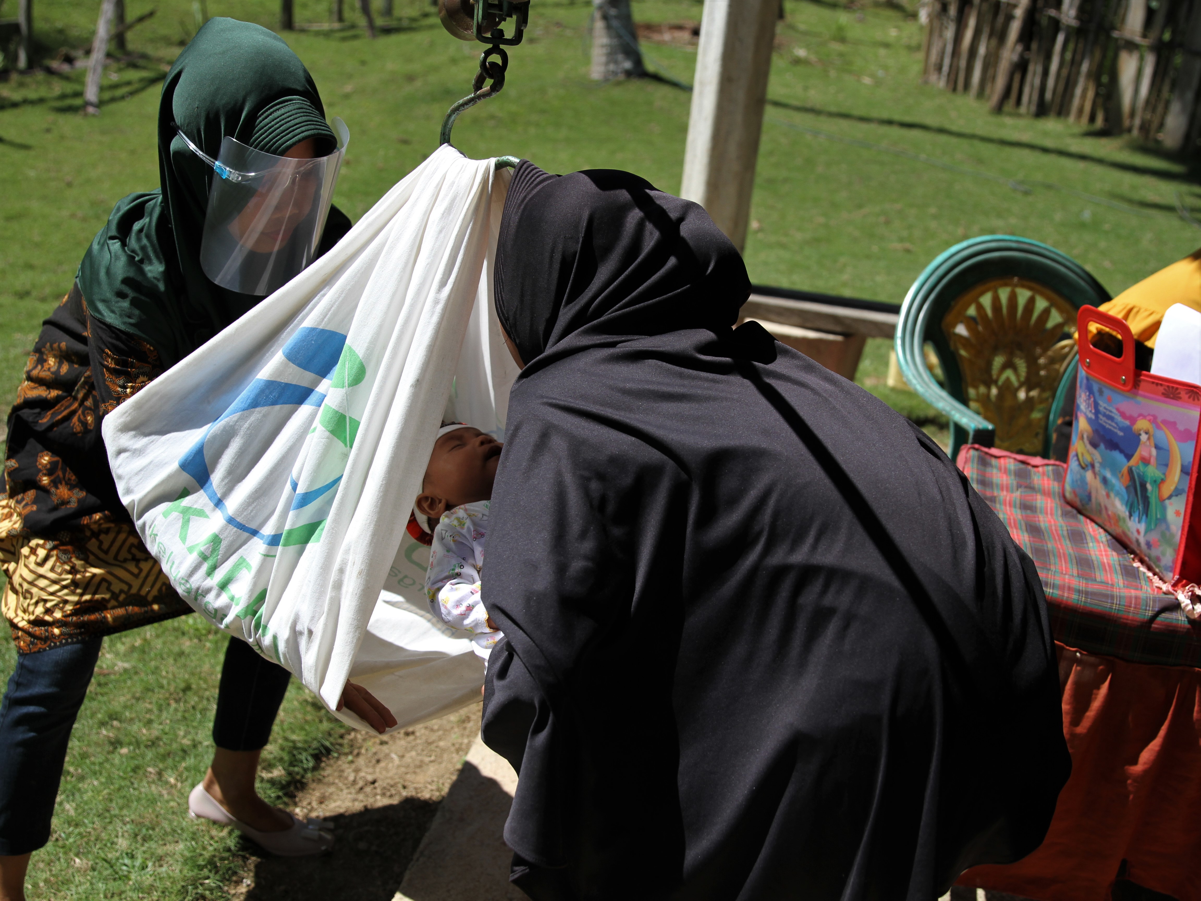 PELAYANAN POSYANDU KELILING Kader Pos Pelayanan Terpadu (Posyandu) menimbang berat badan balita saat kegiatan Posyandu balita 