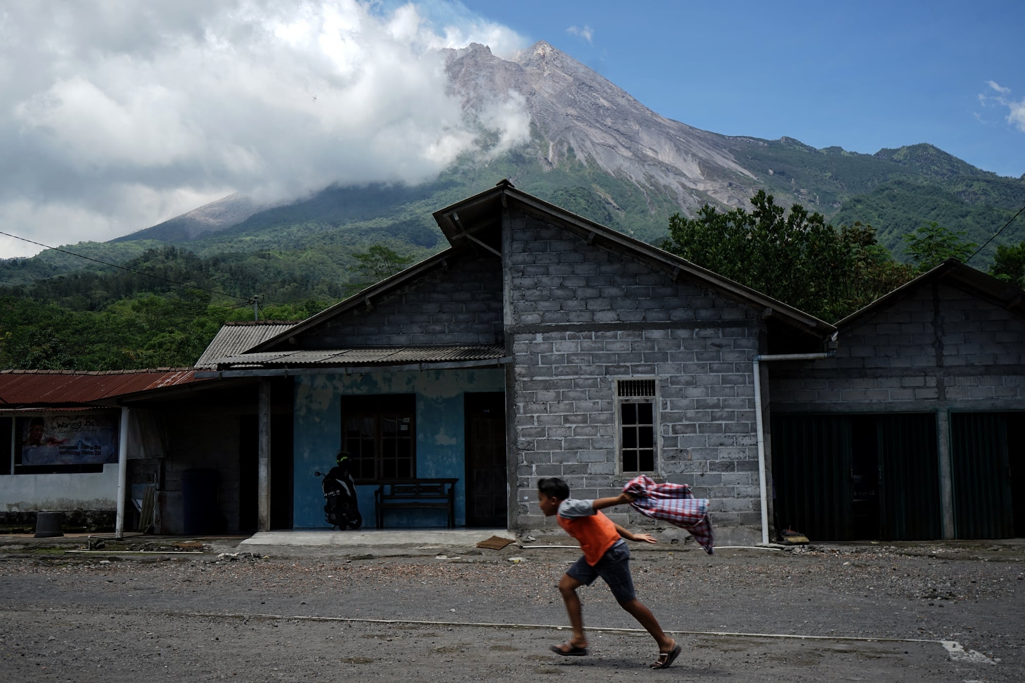  Seorang anak bermain dengan latar belakang Gunung Merapi di kawasan Kinahrejo, Cangkringan, Sleman, D.I Yogyakarta, Rabu (18/11).