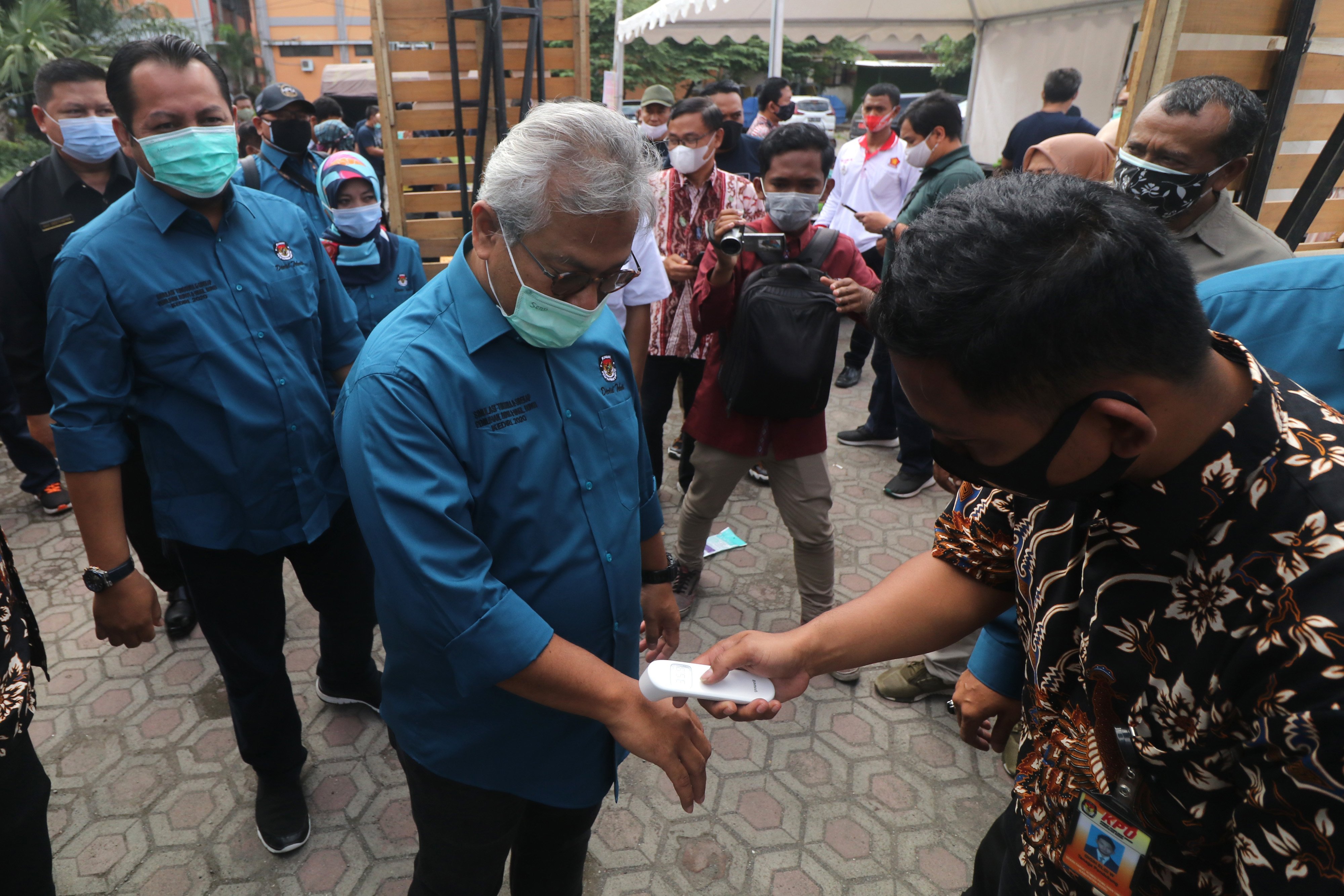 Petugas mengukur suhu tubuh Ketua KPU Arief Budiman (tengah) saat menghadiri simulasi nasional pemungutan suara pilkada serentak di Kediri.