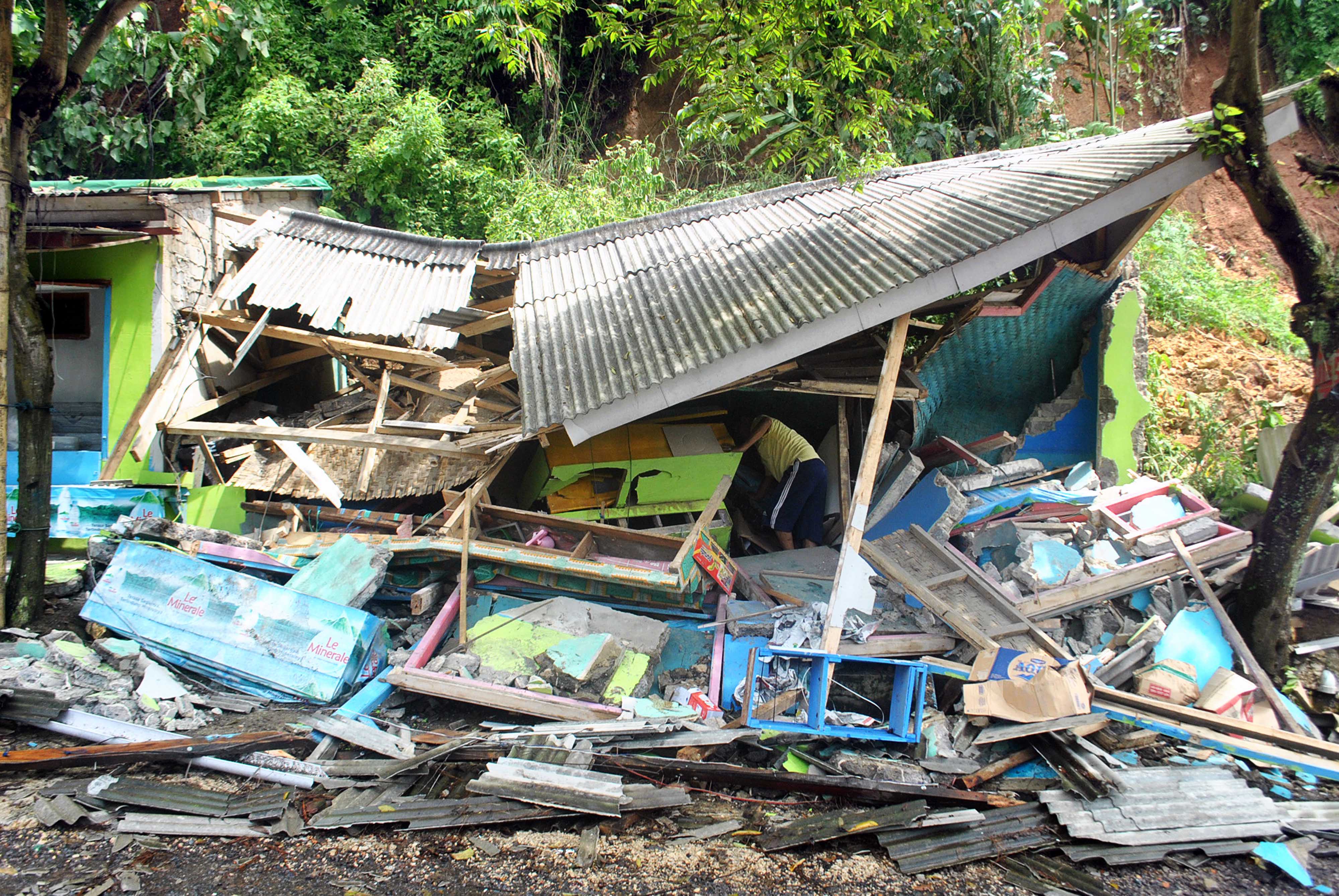  Warga membersihkan puing warung makan miliknya yang ambruk akibat longsor di jalan Cianjur-Jonggol, Cikalong Kulon,Cianjur, Sabtu (10/3).