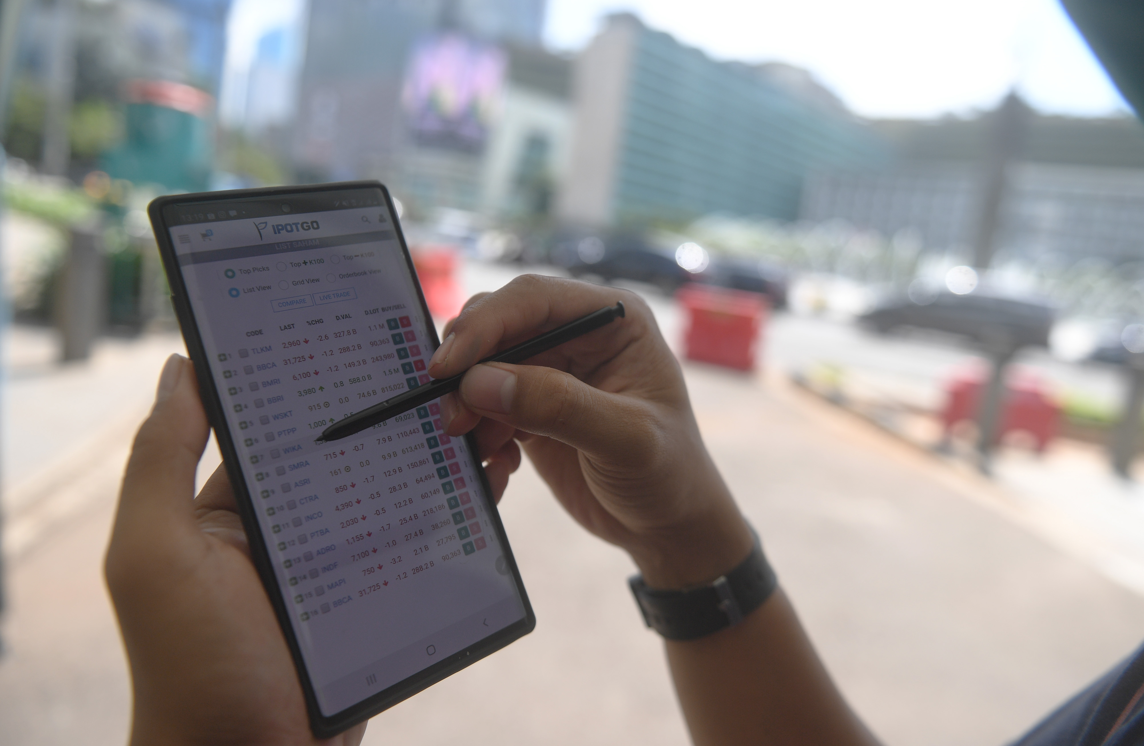 Ilustrasi investor memantau perdagangan saham melalui gawainya.