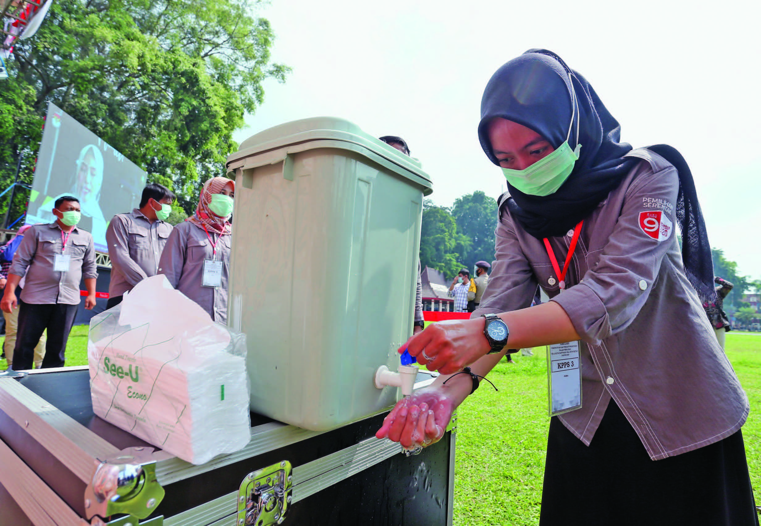 SIMULASI PEMUNGUTAN SUARA: Petugas KPPS mencuci tangan sebelum memasuki area tempat pemungutan suara (TPS) saat simulasi pemungutan suara 