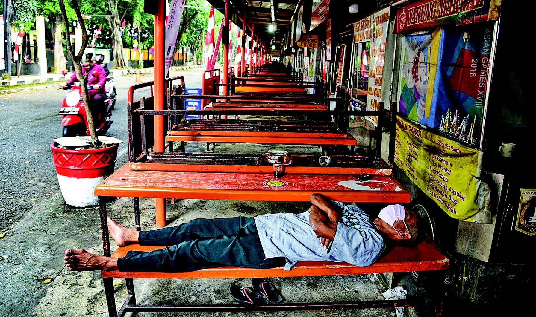 Seorang pedagang tidur di pusat jajanan serbaada (pujasera) yang tutup sementara di Blok S, Kebayoran Baru, Jakarta Selatan, Jumat (14/8).