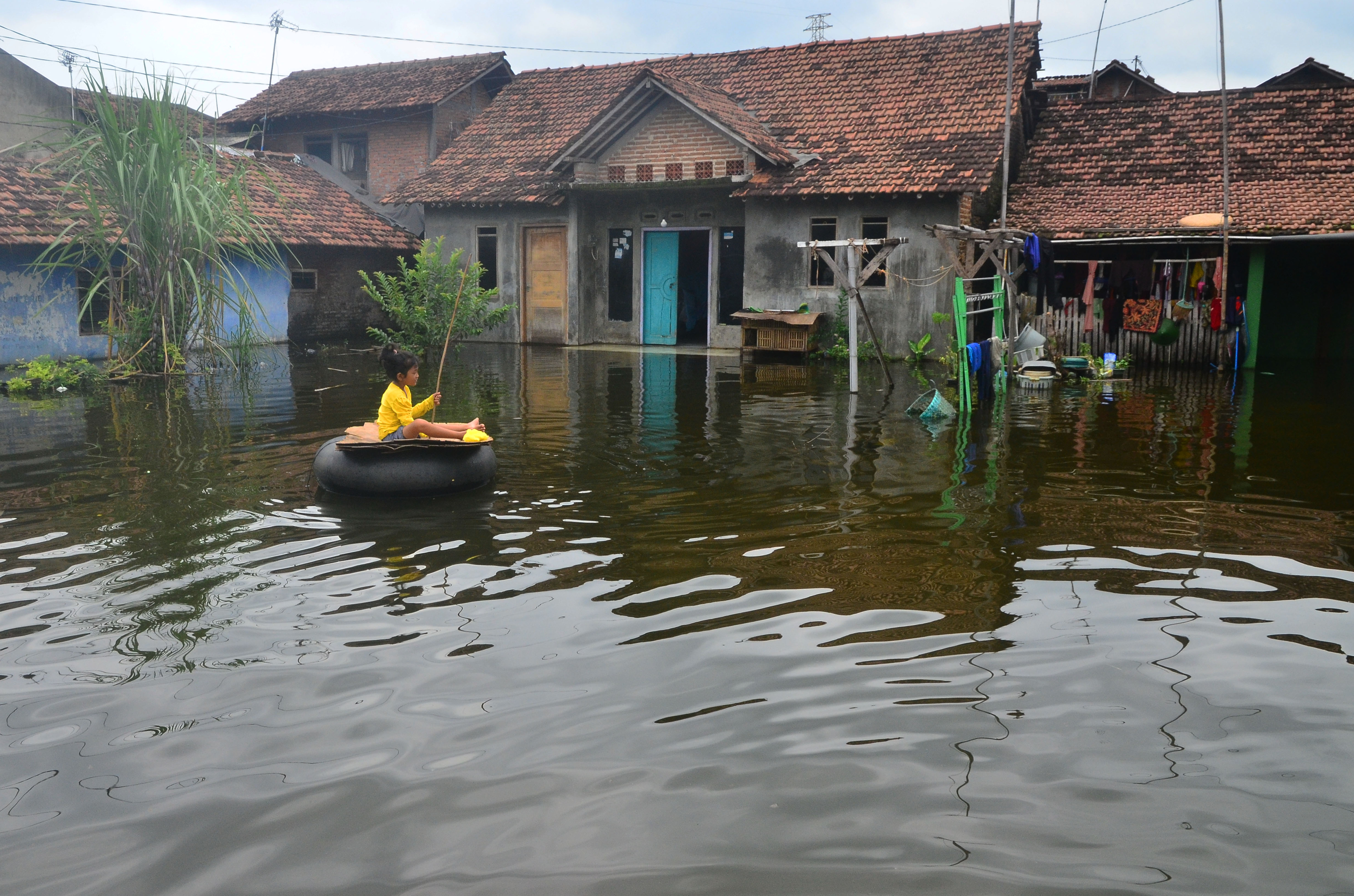 Seorang anak bermain di halaman rumah yang tergenang banjir di Dukuh Tanggulangin, Jati, Kudus, Jawa Tengah, kemarin.