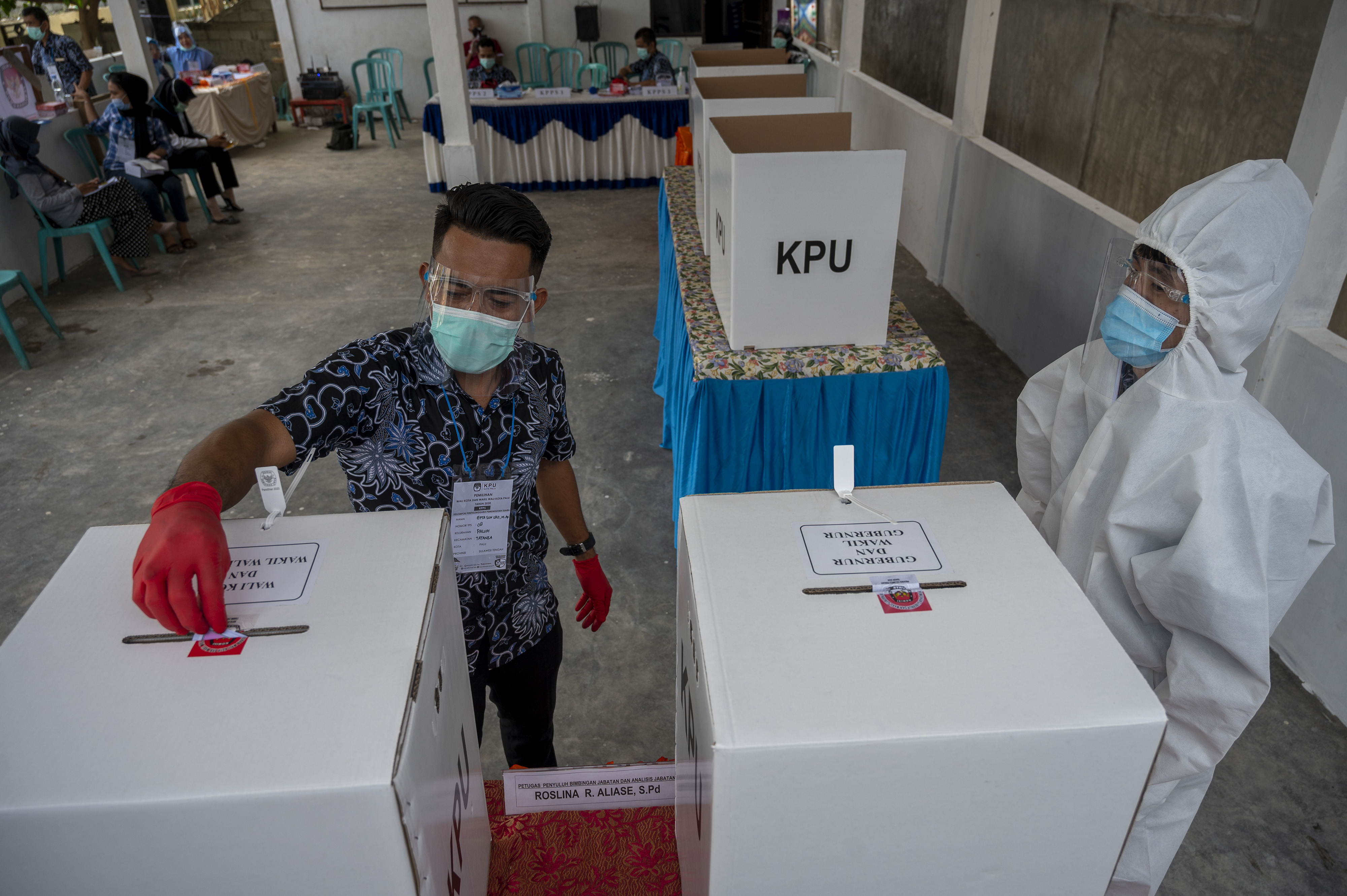 Petugas KPPS mengenakan alat pelindung diri saat bertugas pada Pilkada Serentak di TPS 08, Kelurahan Palupi, Palu, Sulawesi Tengah.