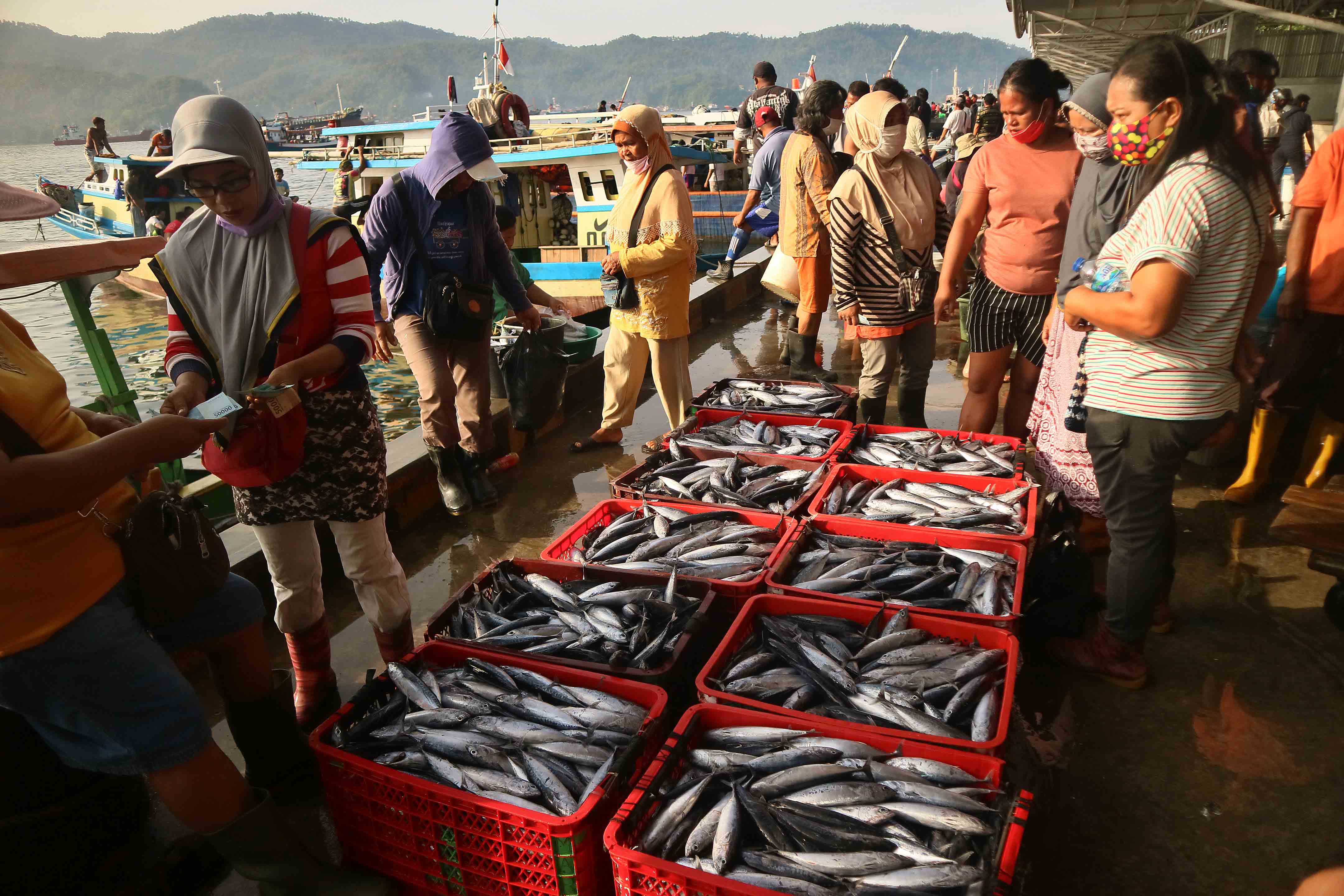 Kesibukan transaksi jual beli ikan antara nelayan dengan pedagang saat hasil tangkapan ikan turun di dermaga TPI Aertembaga, Bitung