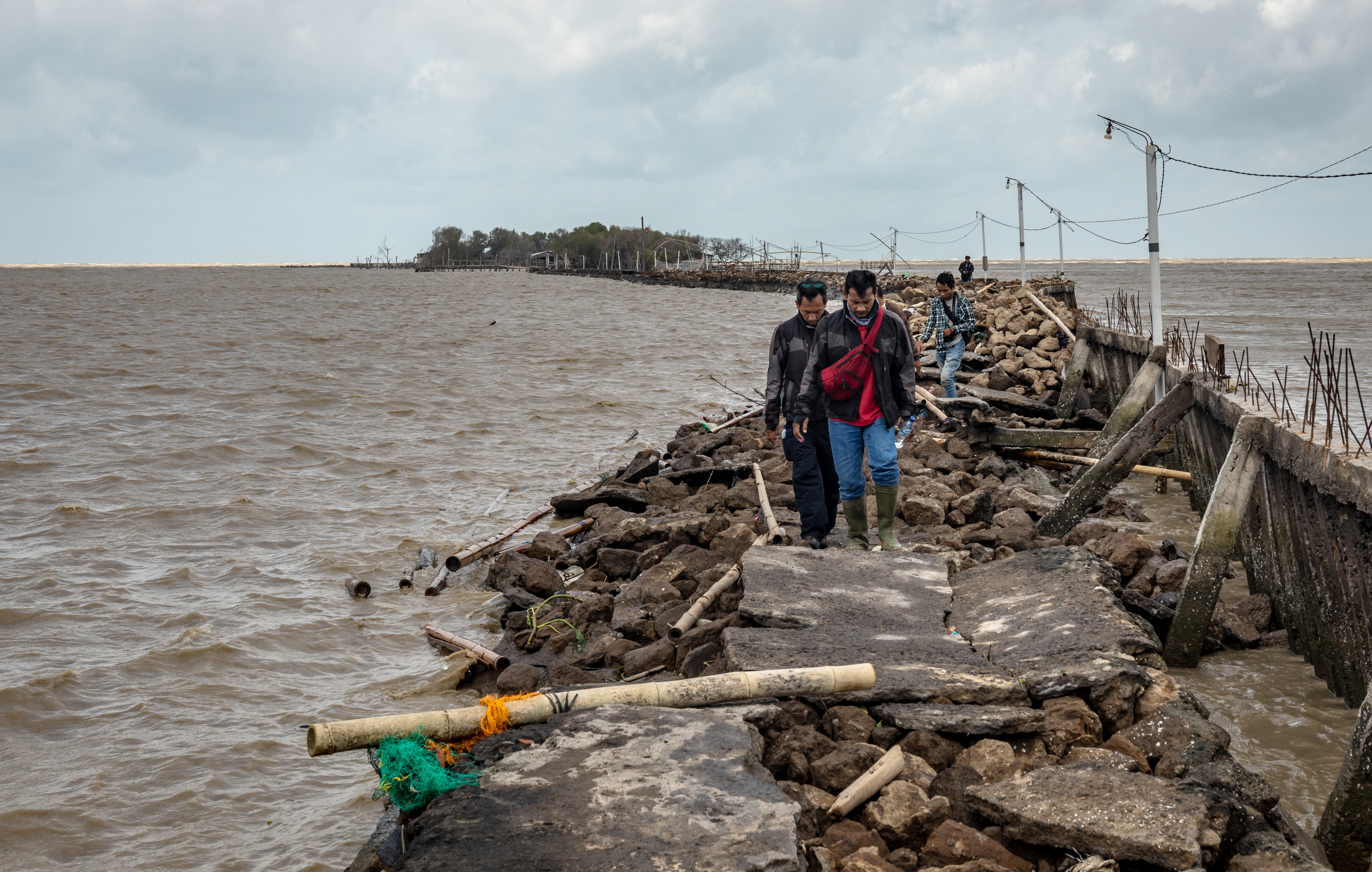 Sejumlah warga melewati jalan rusak akibat terjangan ombak di Desa Bedono, Sayung, Demak, Jawa Tengah, Selasa (8/12).