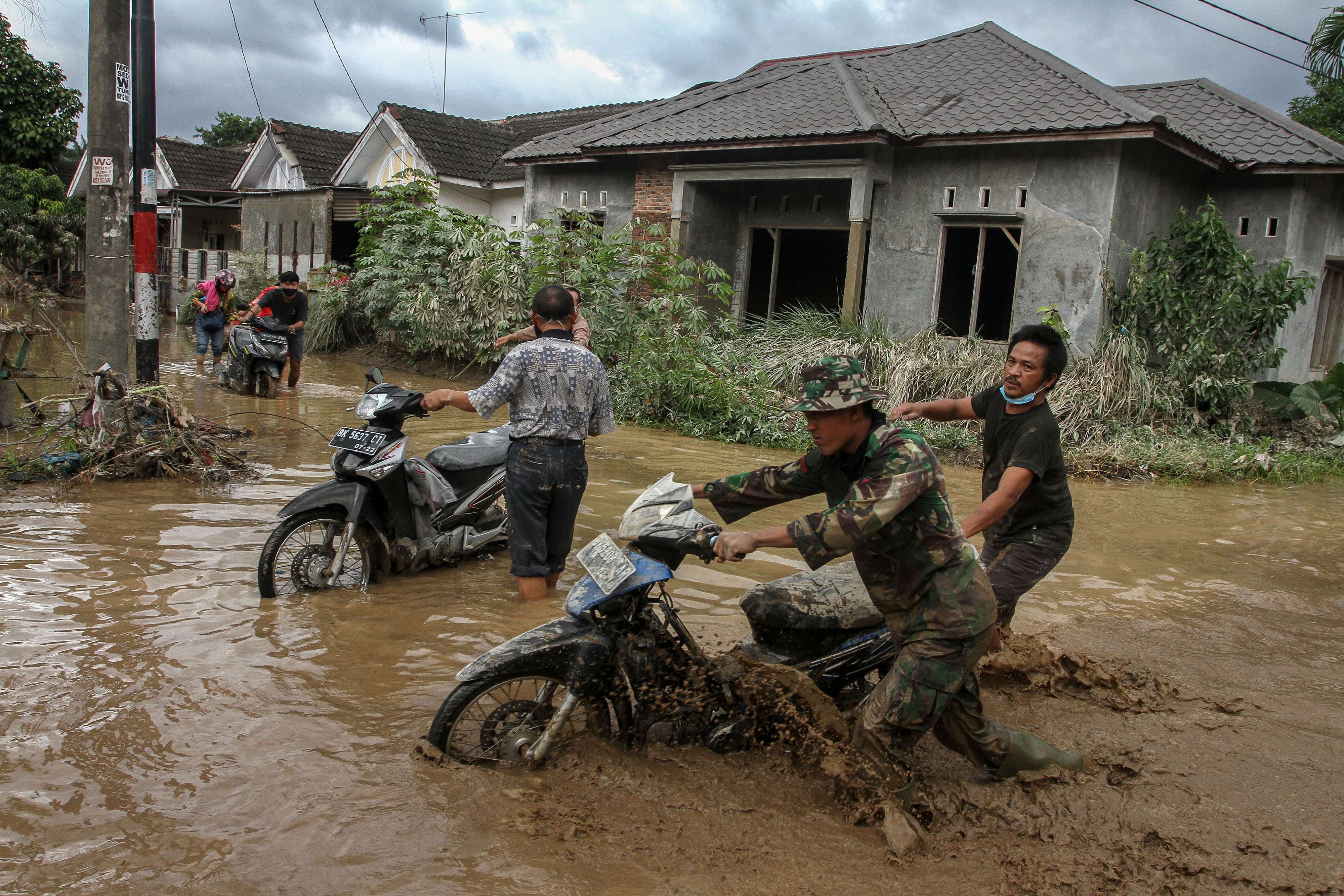 Prajurit TNI dibantu relawan mengevakuasi warga dan kendaraan dari rumahnya pascabanjir di Perumahan De Flamboyan, Medan, Sumut, kemarin.
