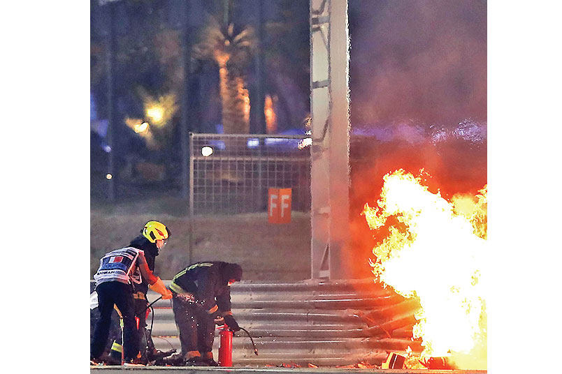 PADAMKAN API: Petugas berupaya memadamkan api yang membakar mobil pembalap Haas Romain Grosjean di GP Bahrain, Minggu (29/11).