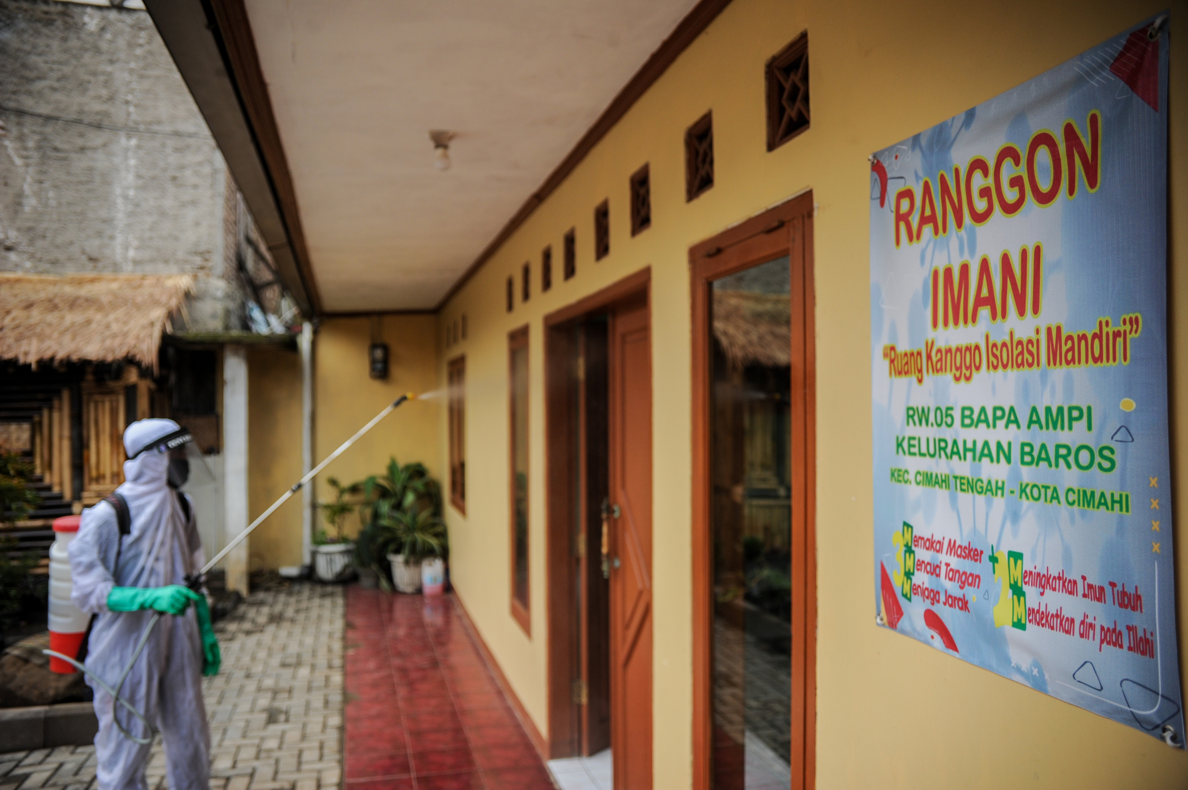 eorang pengurus RW menyemprotkan cairan disinfektan di sebuah ruangan isolasi mandiri di Baros, Cimahi, Jawa Barat, Minggu (29/11).