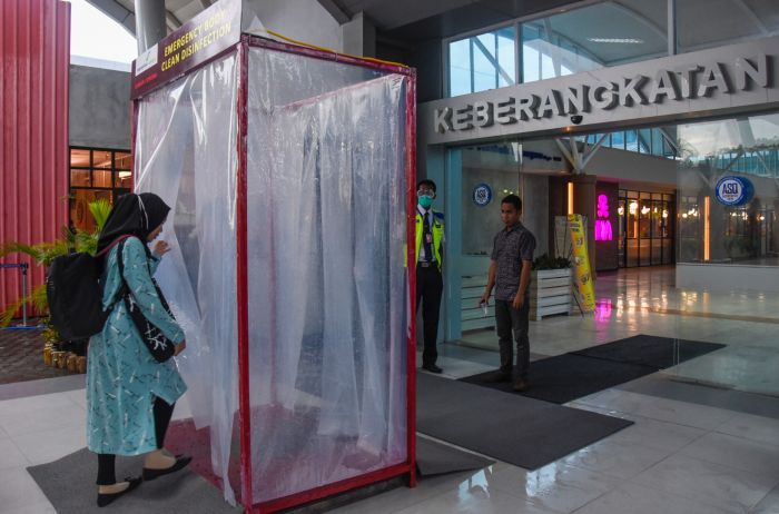 Penumpang memasuki bilik disinfektan yang terpasang di pintu keberangkatan Bandara Internasional Lombok.