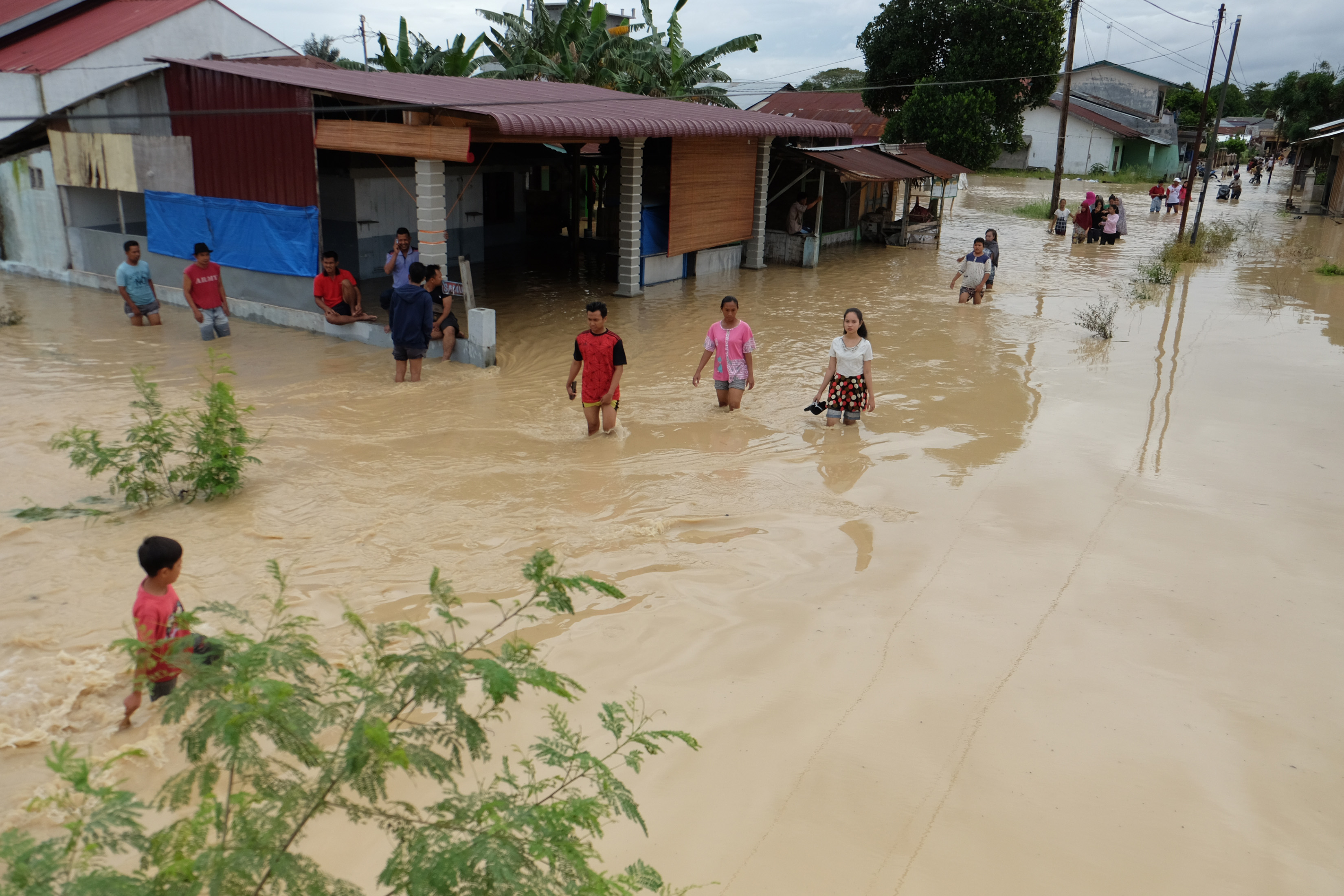  Warga melintasi banjir yang merendam pemukiman penduduk di Kecamatan Sunggal, Deli Serdang, Sumatera Utara, Jumat (4/12/2020)