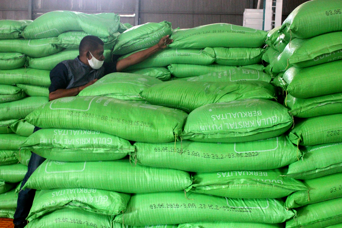 Pekerja menumpuk karung gula