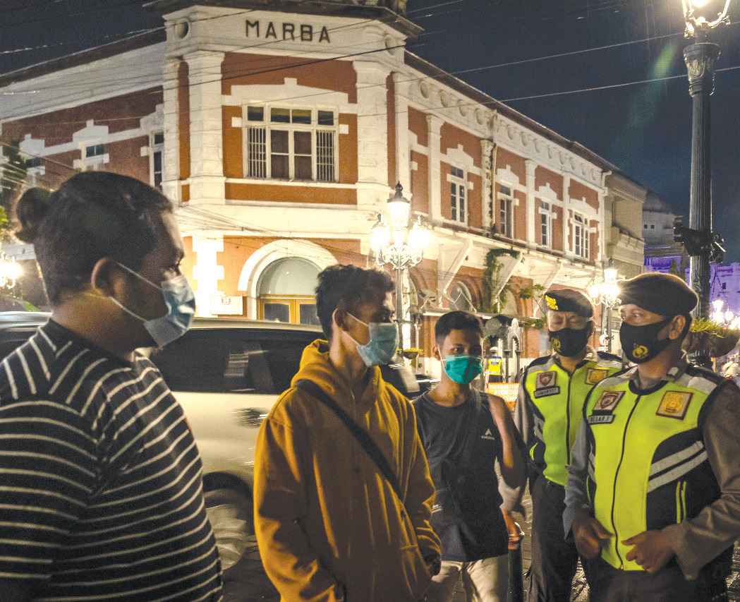 Petugas kepolisian memberikan imbauan protokol kesehatan kepada wisatawan saat operasi yustisi covid-19 di kawasan Kota Lama Semarang.