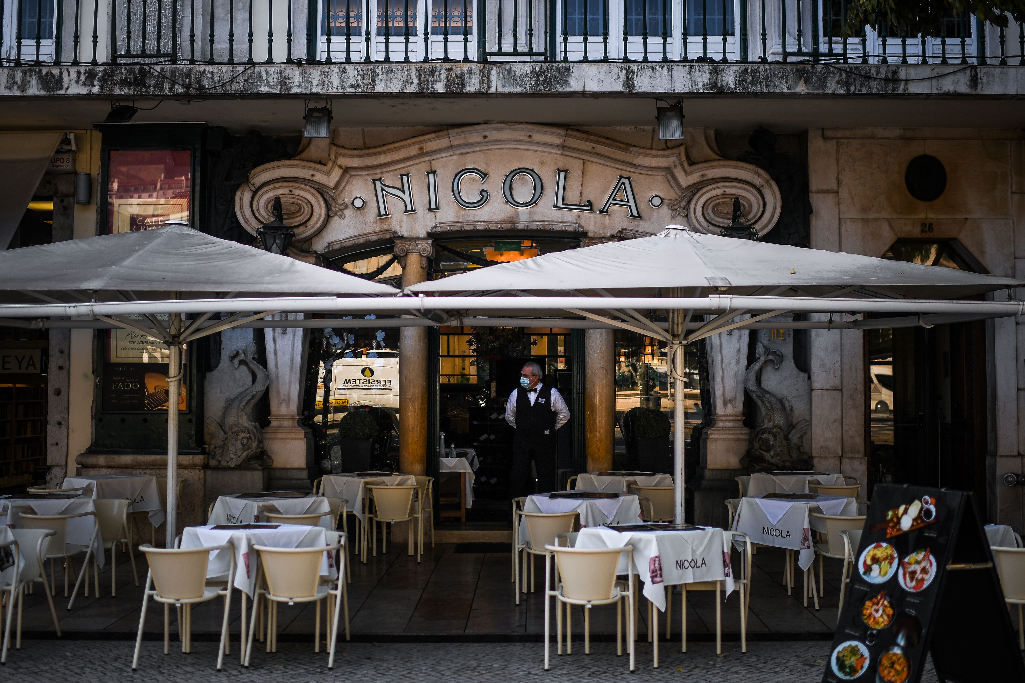 Seorang pelayan mengenakan masker menunggu tamu di sebuah restoran di Lisabon, Portugal.