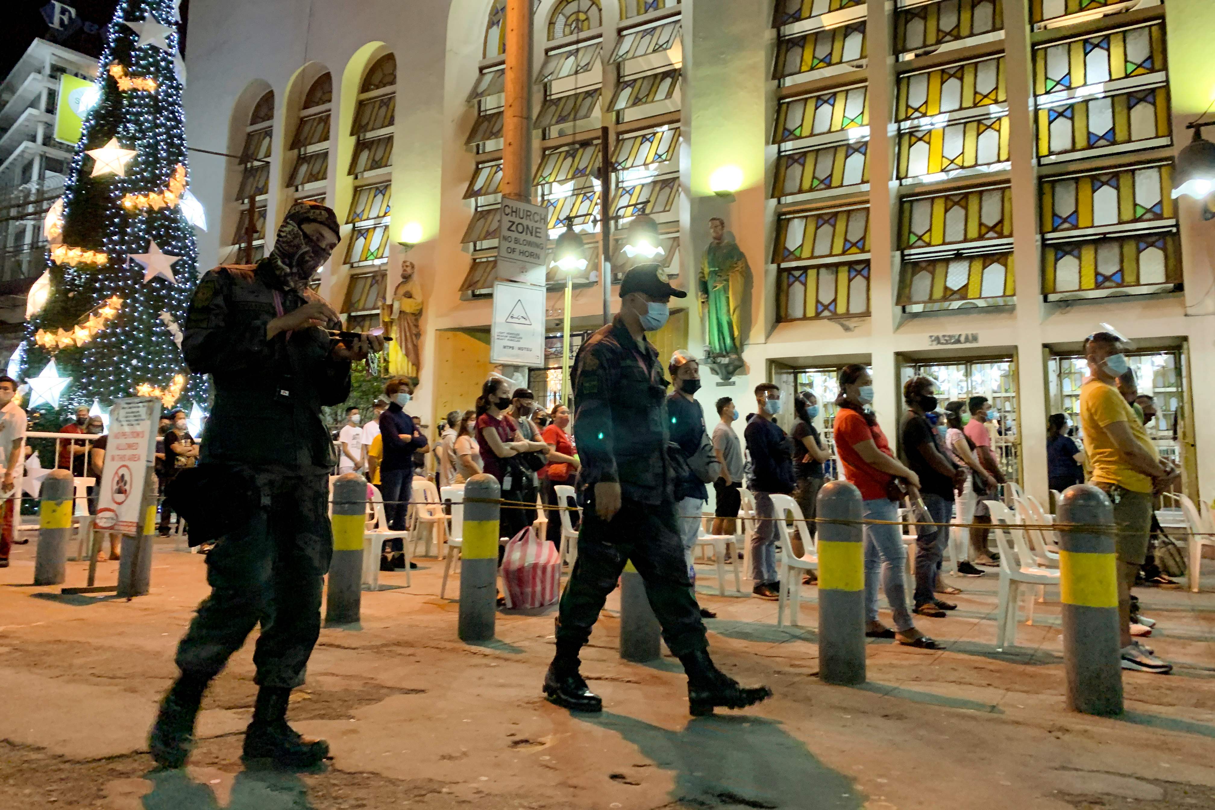 Personel polisi mengawasi jalannya misa Natal di Manila, Filipina untuk memastikan umat tetap menjaga jarak.