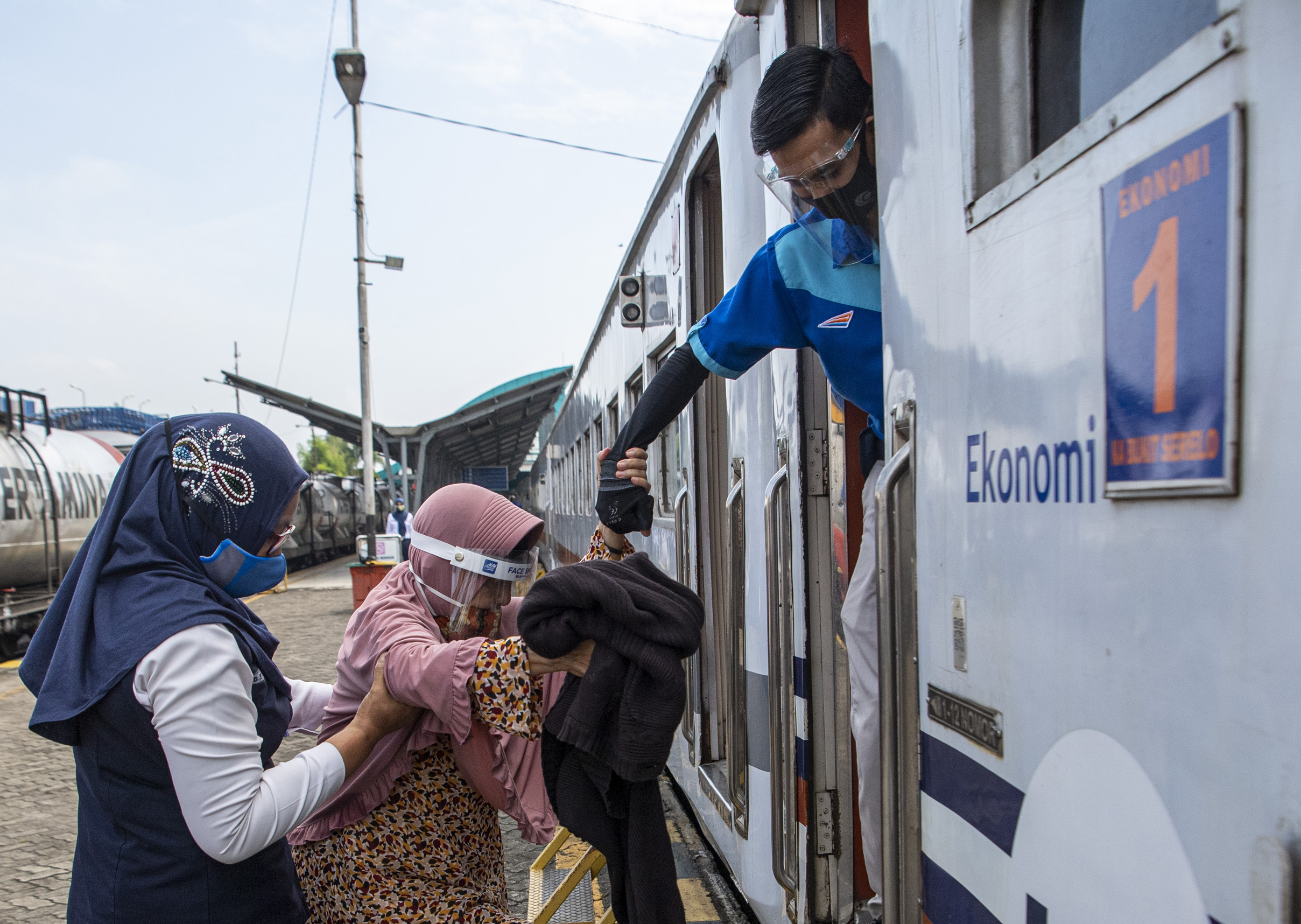 Petugas membantu penumpang kereta yang hendak naik ke dalam gerbong kereta api Serello tujuan Palembang-Lubuklinggau.