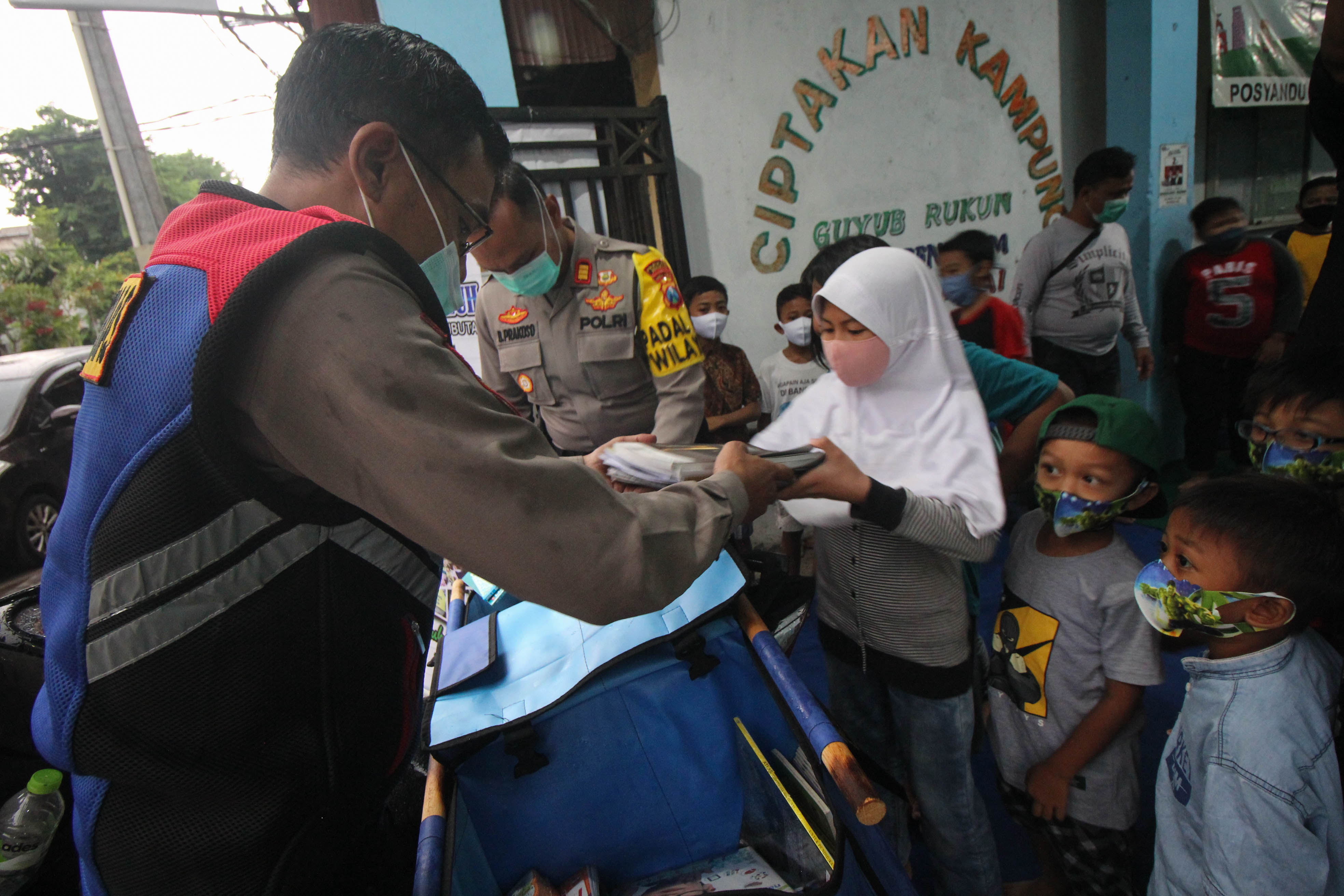 Polisi membagikan buku bacaan kepada sejumlah anak untuk dibaca di kawasan Maspati, Surabaya, Jawa Timur.