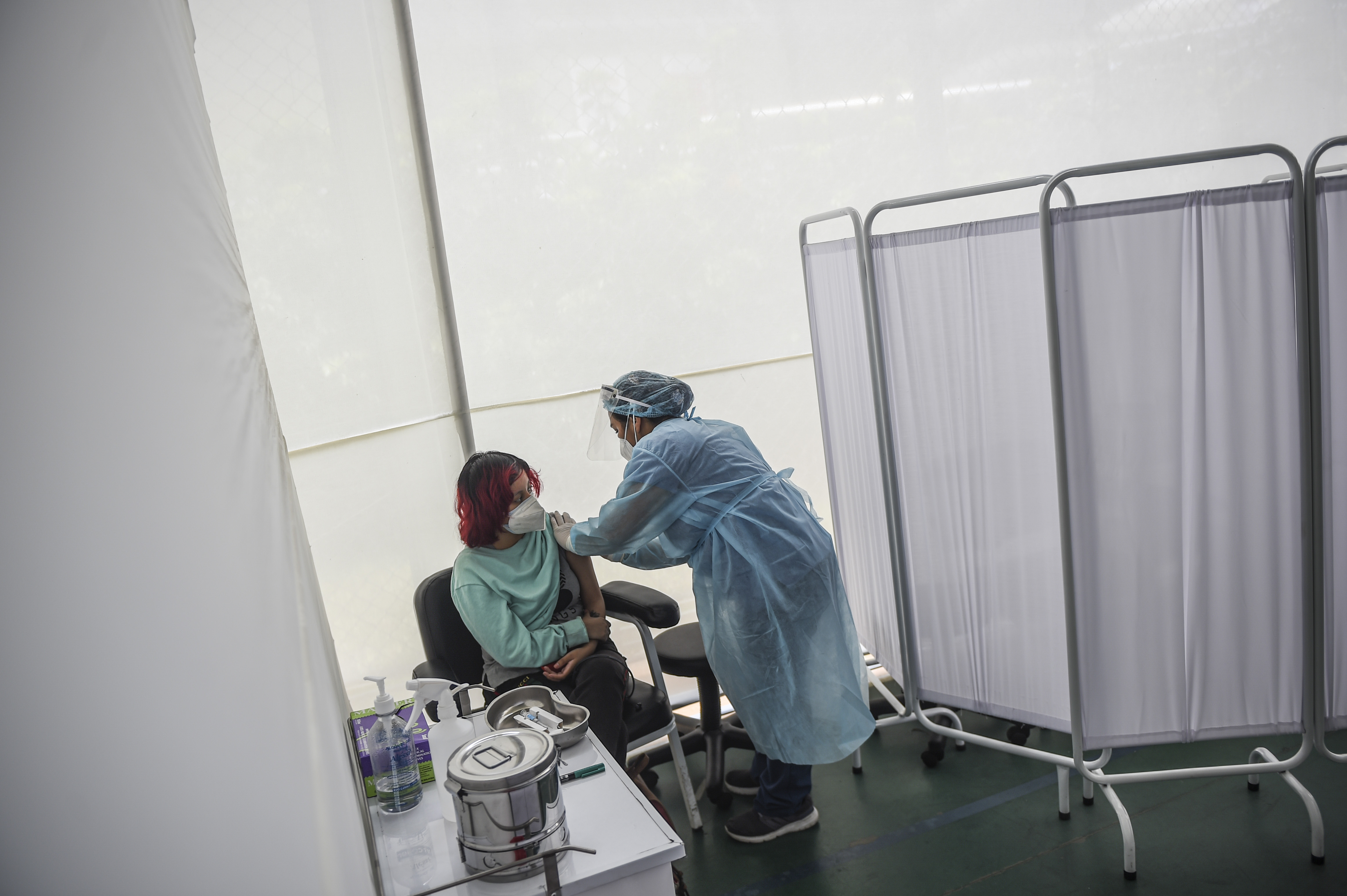 Seorang petugas kesehatan menyuntikan vaksin covid-19 Sinopharm kepada relawan dalam uji klinis di Peru.