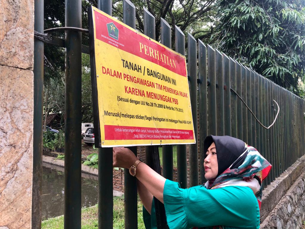 Operasi Penindakan PBB di Malang: Petugas Bapenda Kota Malang, Jawa Timur, memasang papan peringatan bagi wajib pajak.