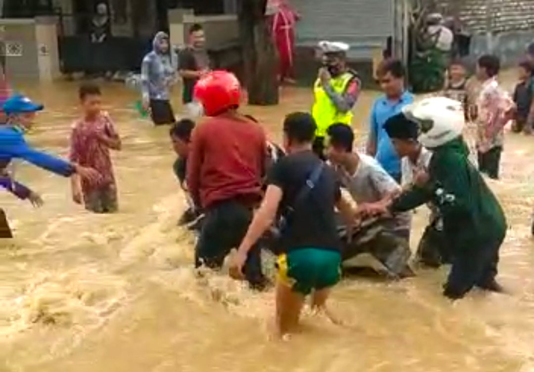 Warga membantu mendoromg kendaraan yang macet akibat terjebak banjir di Kecamatan Blega, Kabupaten Bangkalan, Jawa Timur, Rabu (30/12).
