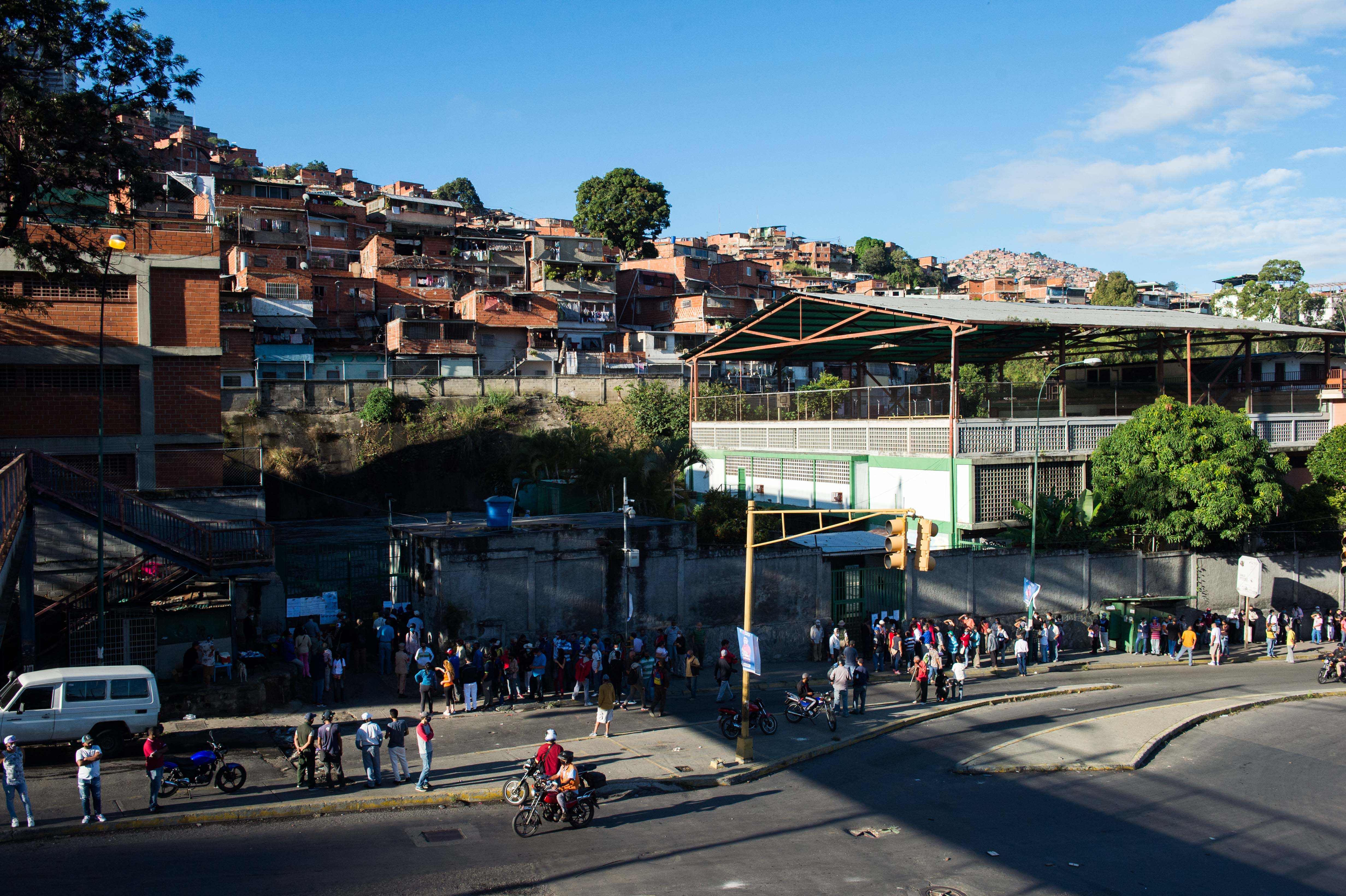 Warga antri di depan sebuah sekolah di Kota Caracas, Venezuela untuk melakukan pemilihan legislator, Minggu (6/12/2020)