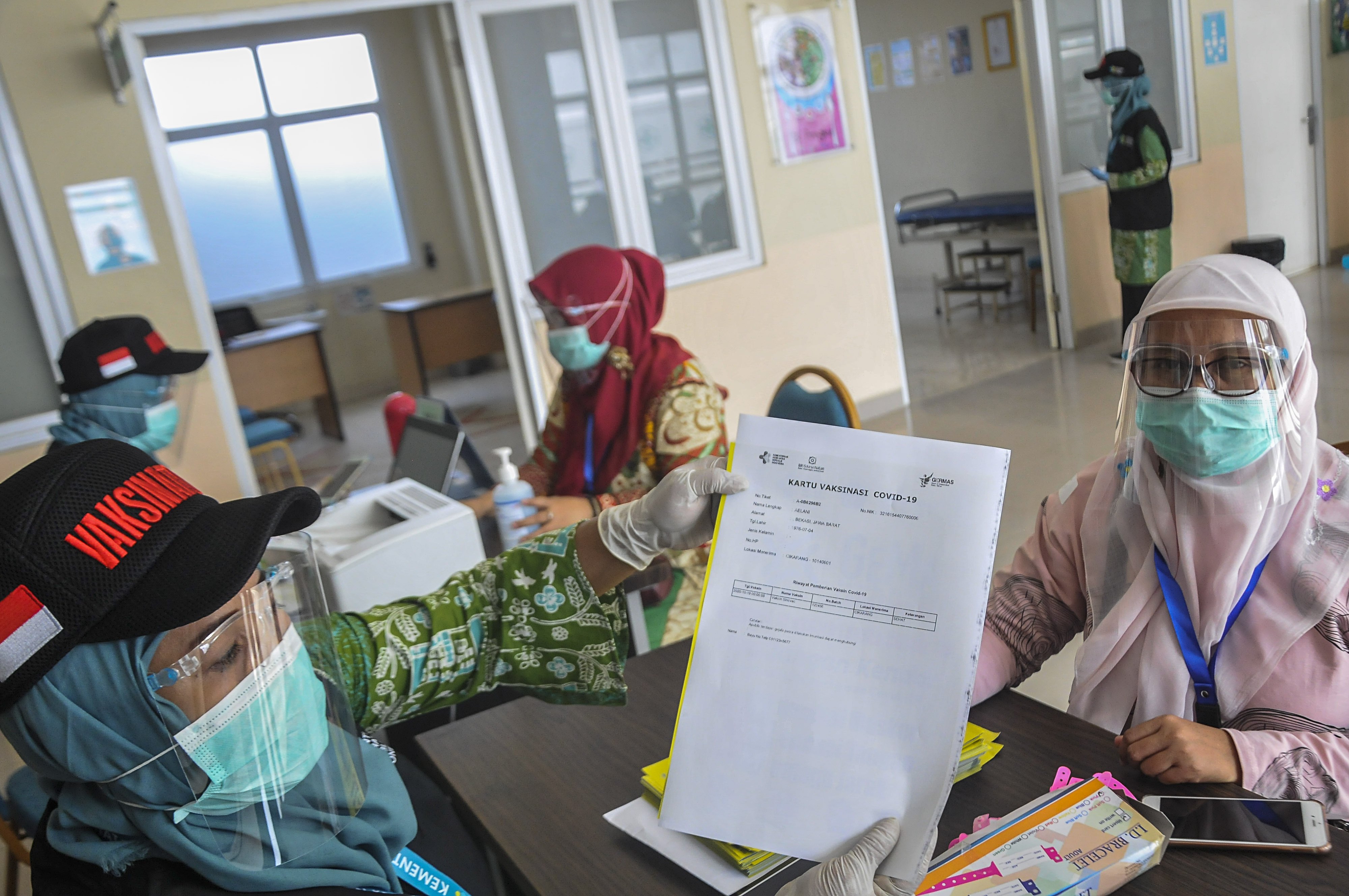 Petugas medis memberikan surat vaksinasi COVID-19 kepada warga saat simulasi 