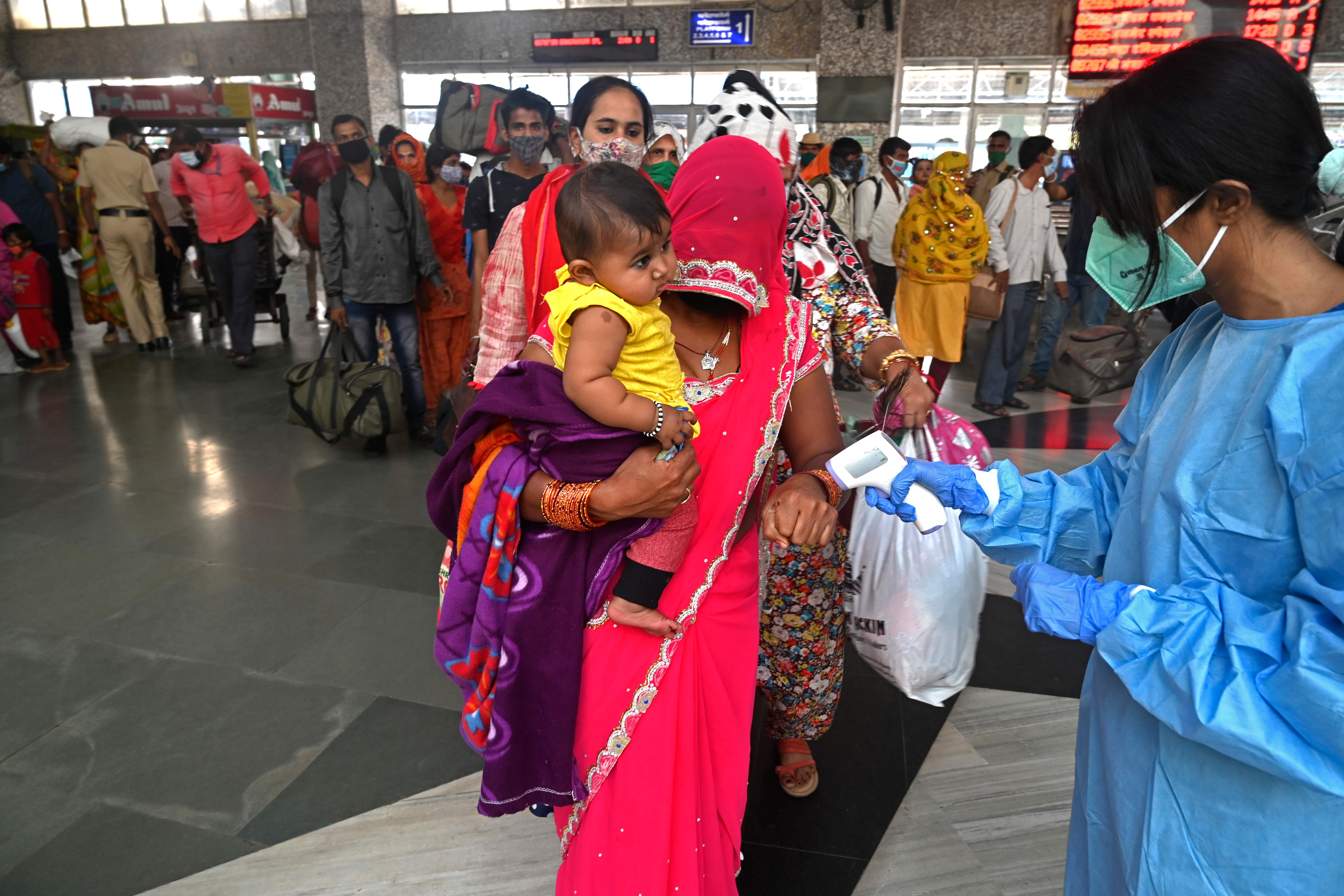 Seorang petugas kesehatan memeriksa suhu tubuh penumpang kereta api setibanya di stasiun, di Mumbai, kemarin.