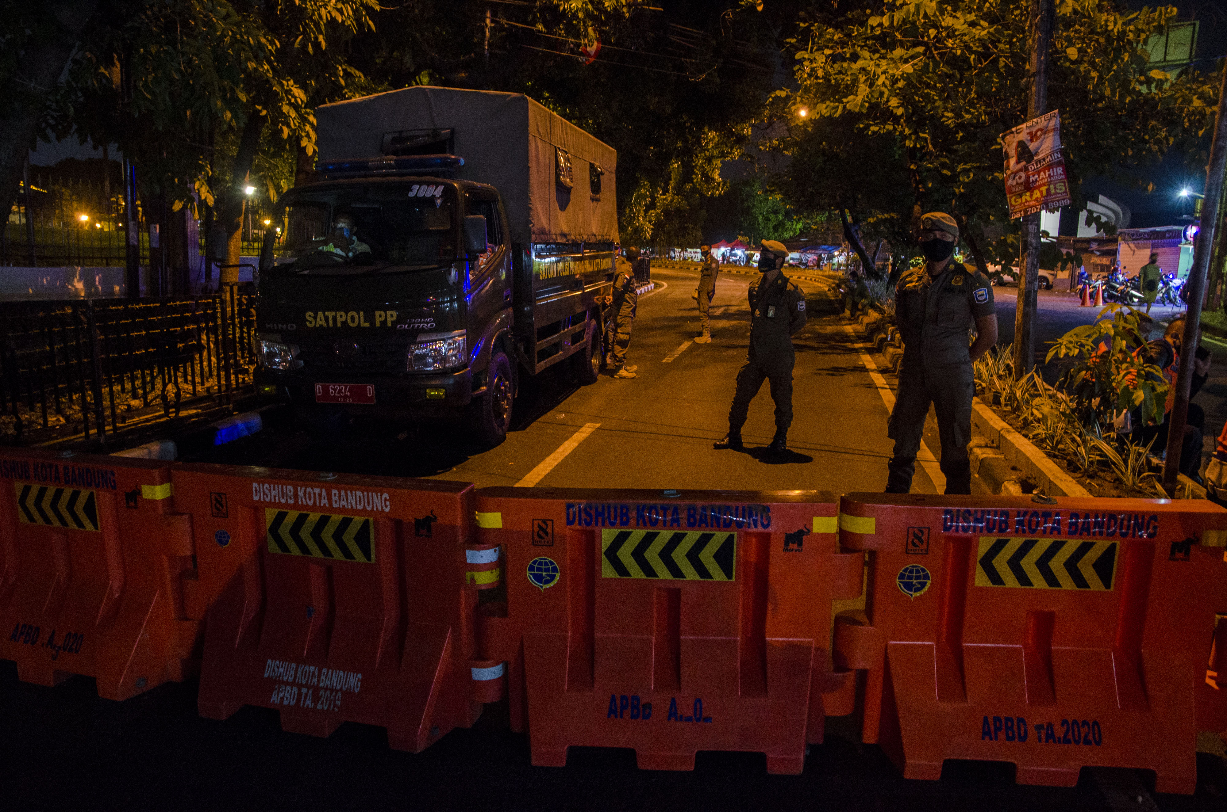Petugas Satpol PP Kota Bandung berjaga di ruas jalan Dipatiukur yang ditutup pada penerapan PSBB proporsional di Bandung, Sabtu (5/12).