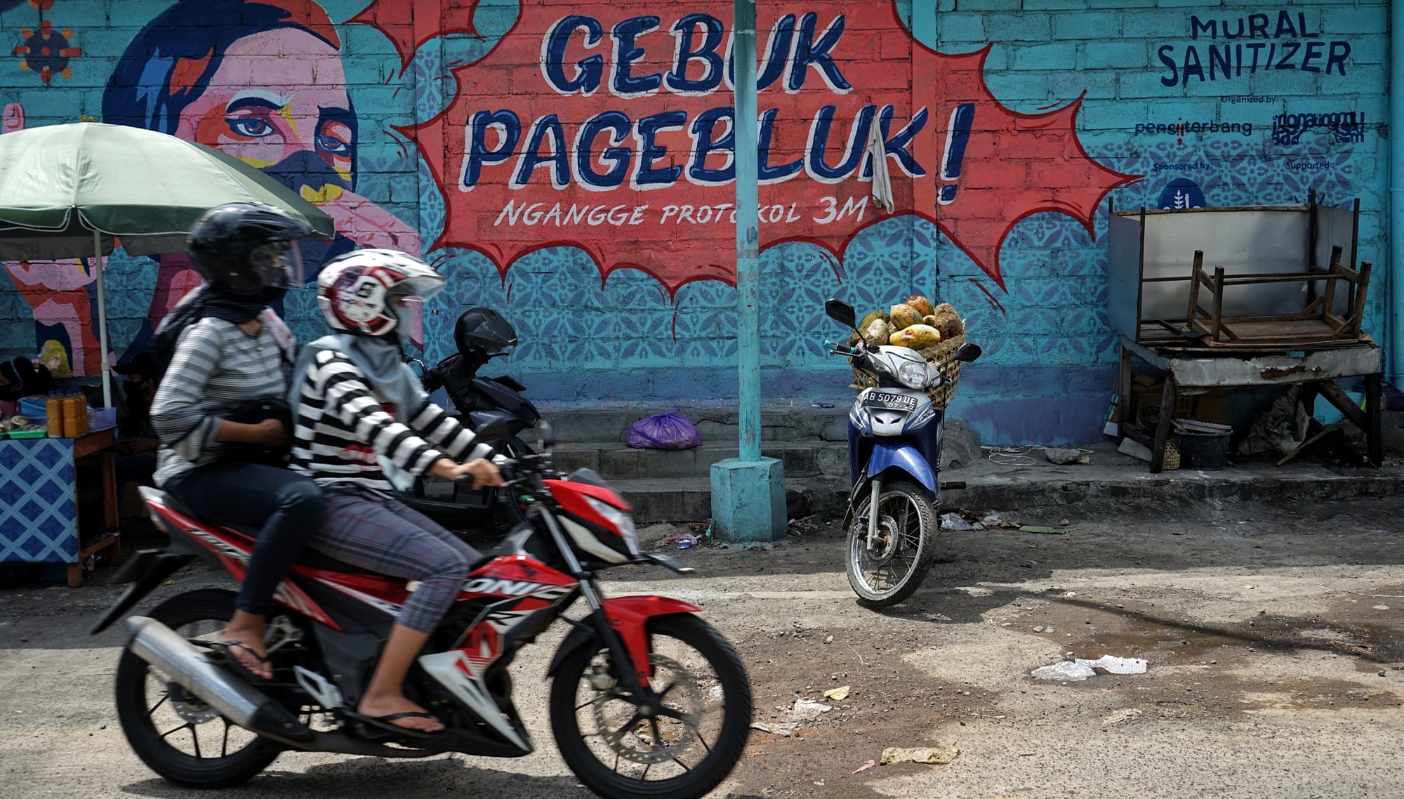 Warga melintasi mural bertema COVID-19 di kawasan Serangan, Yogyakarta, Gubernur DIY membatasi operasional mall hingga obyek wisata.